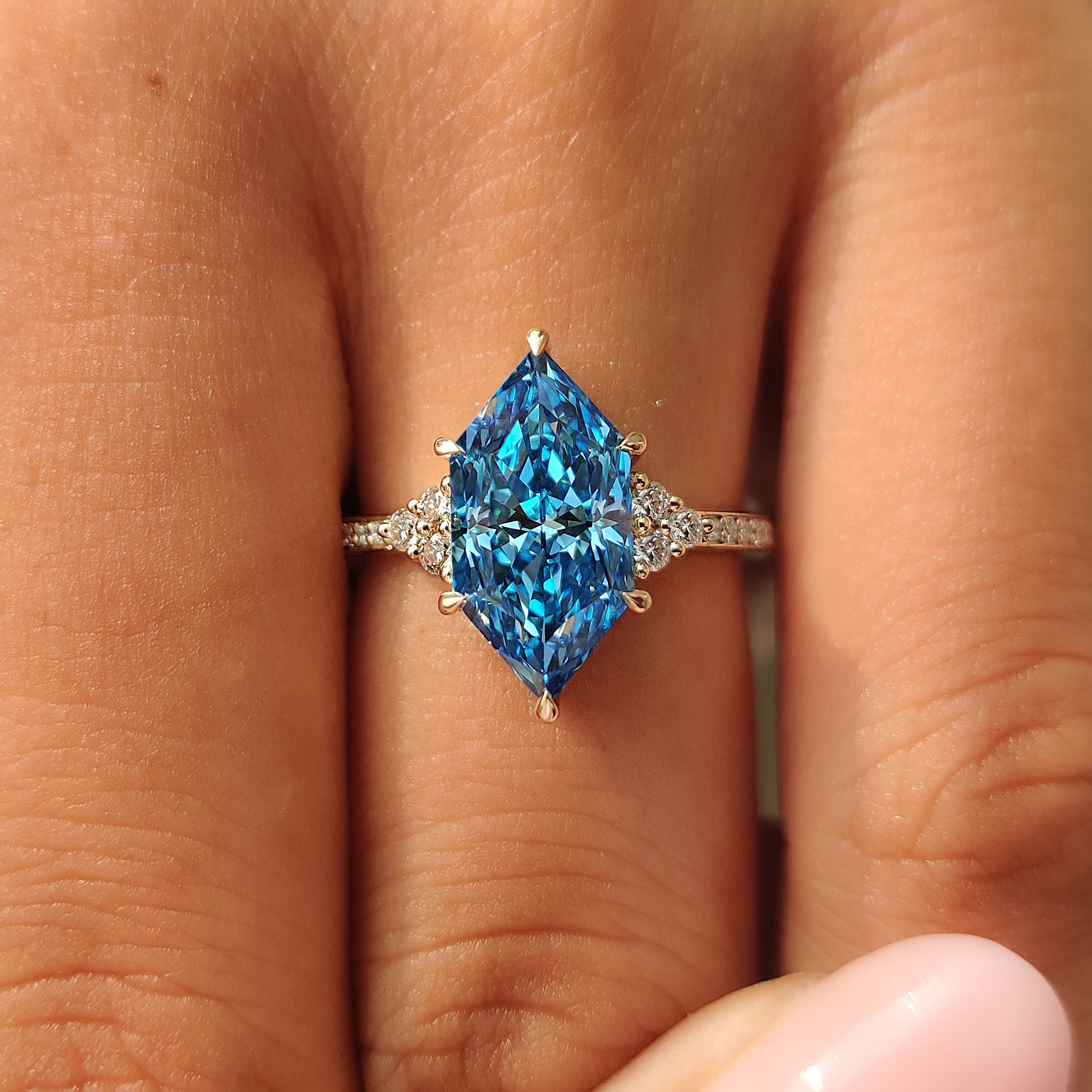 Yellow gold ring with a blue Dutch marquise center diamond.
