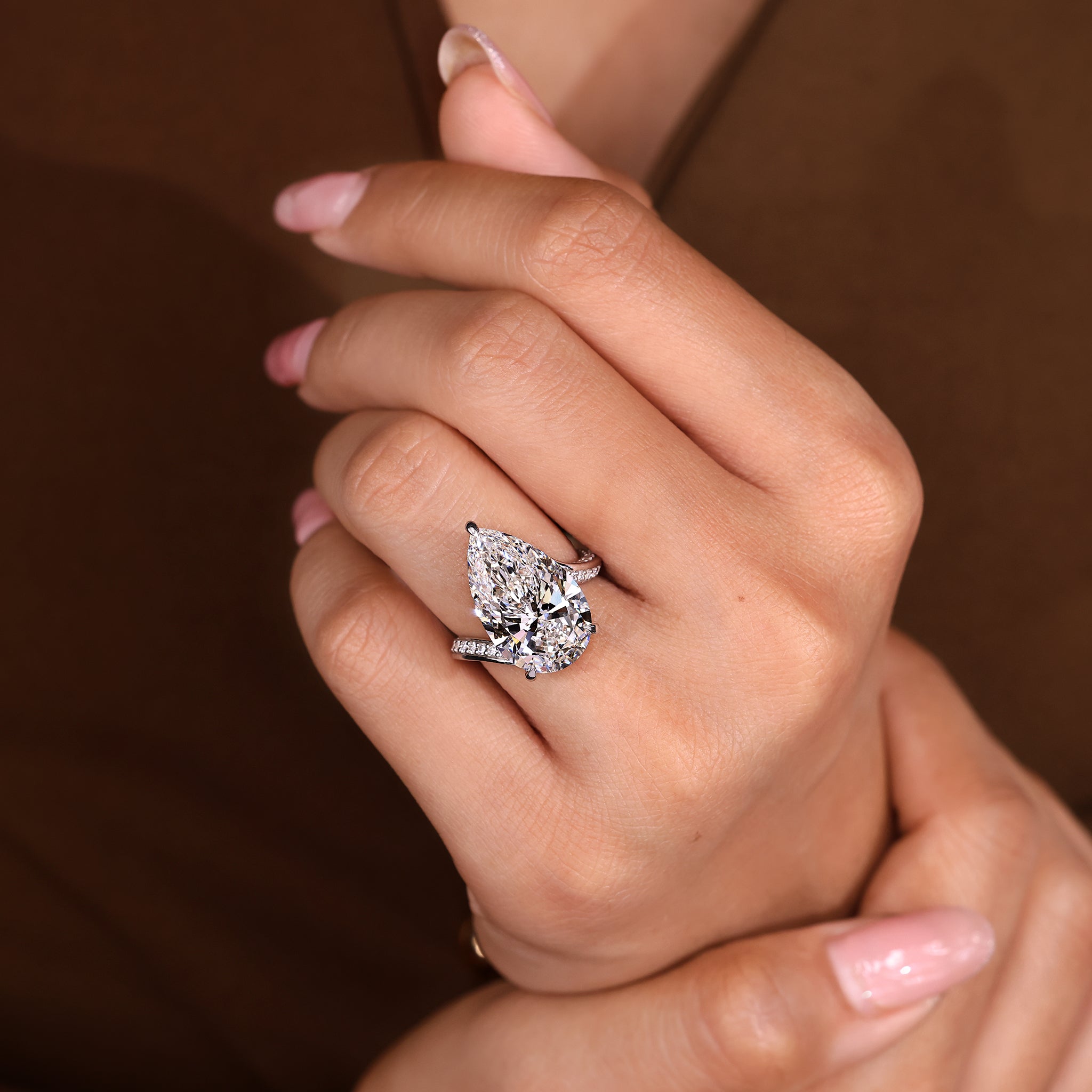 Bypass style pear diamond ring accented by round diamond double pave band.
