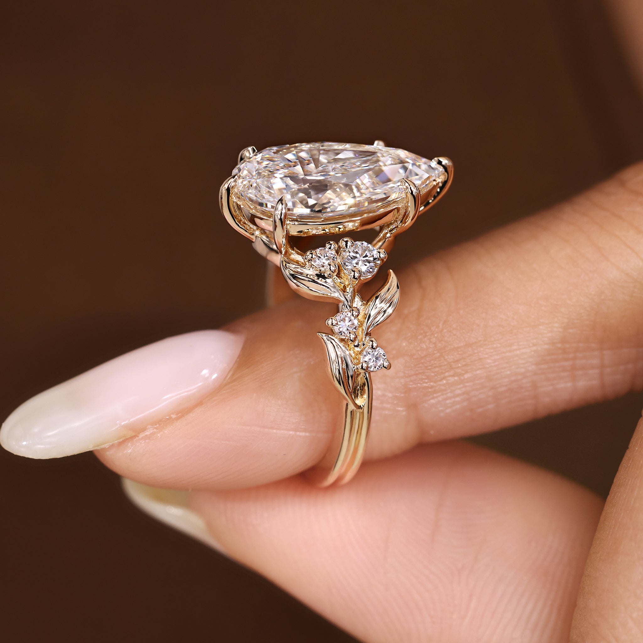 Pear shaped diamond ring with round side stones and nature inspired design
