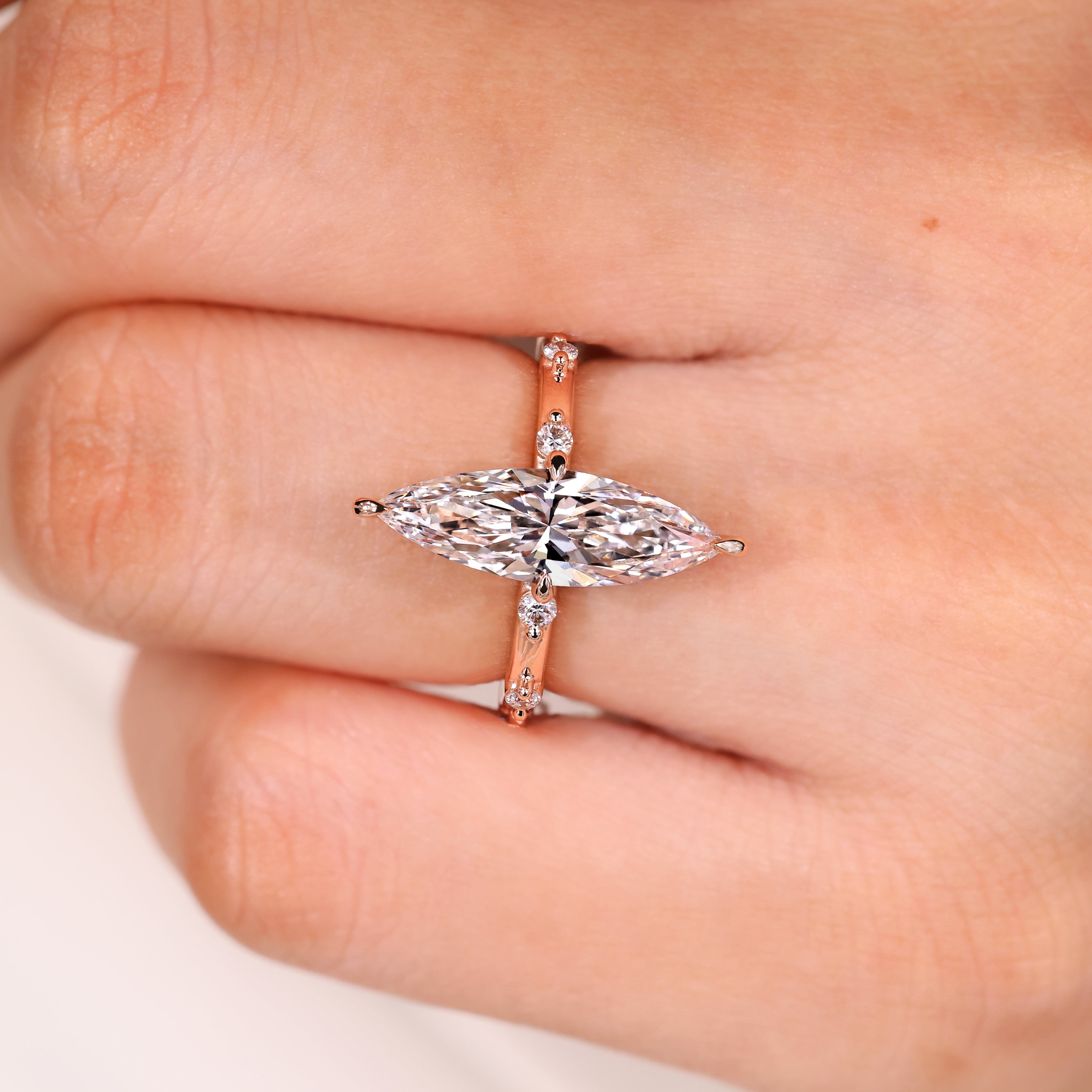 Elongated marquise ring with round diamond pave accents
