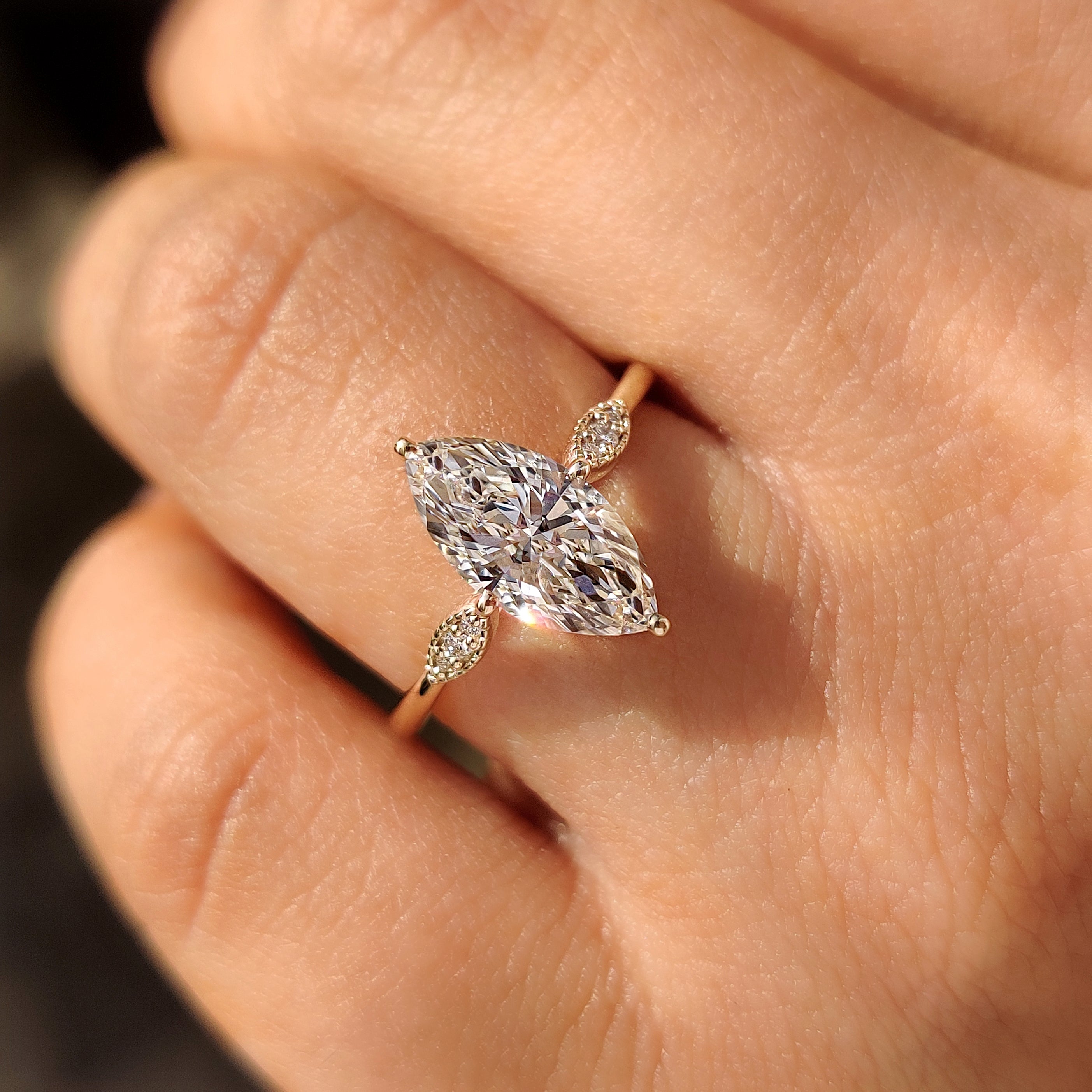 Marquise shape ring featuring cathedral setting and round stones.
