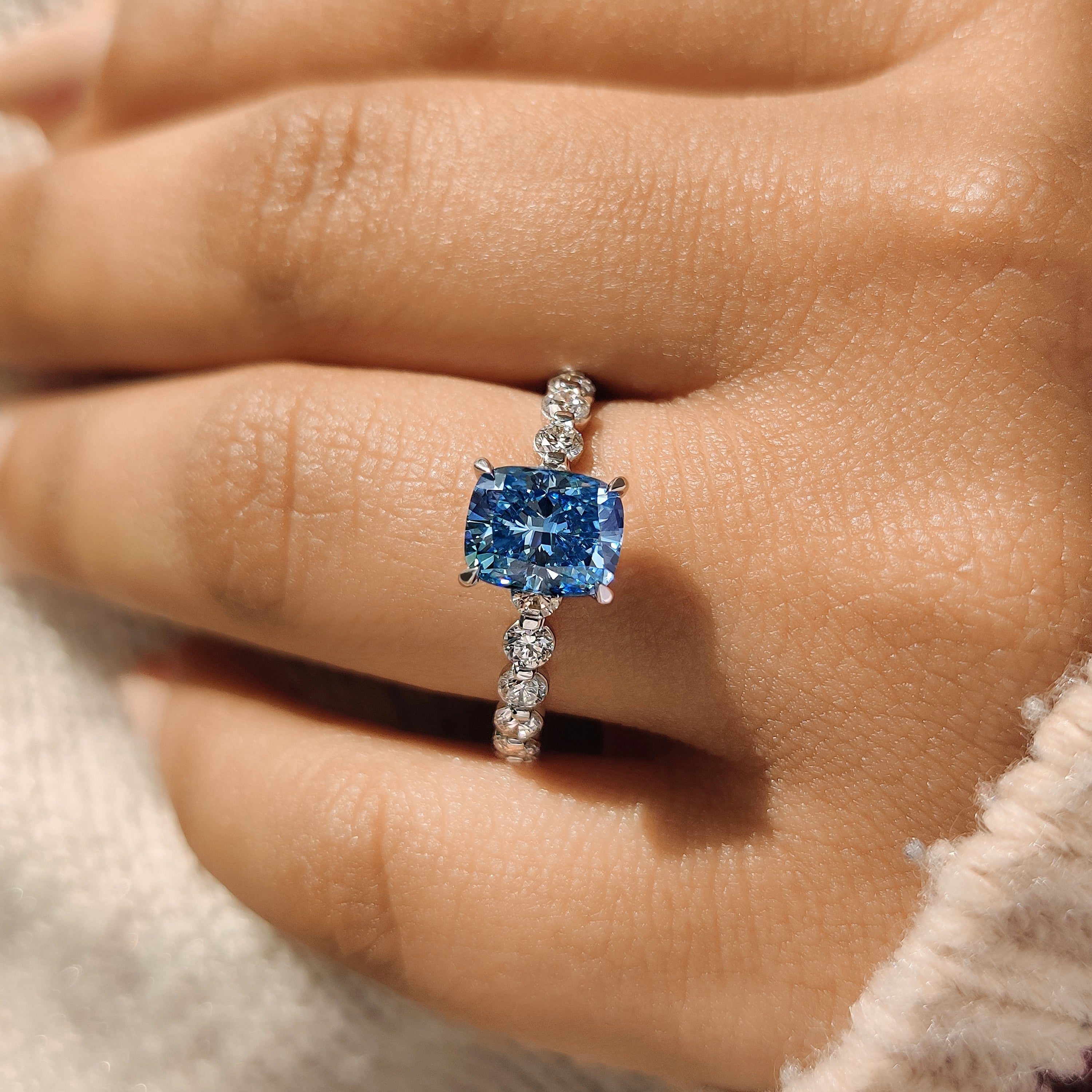 Blue cushion diamond ring with floating bubble pave.
