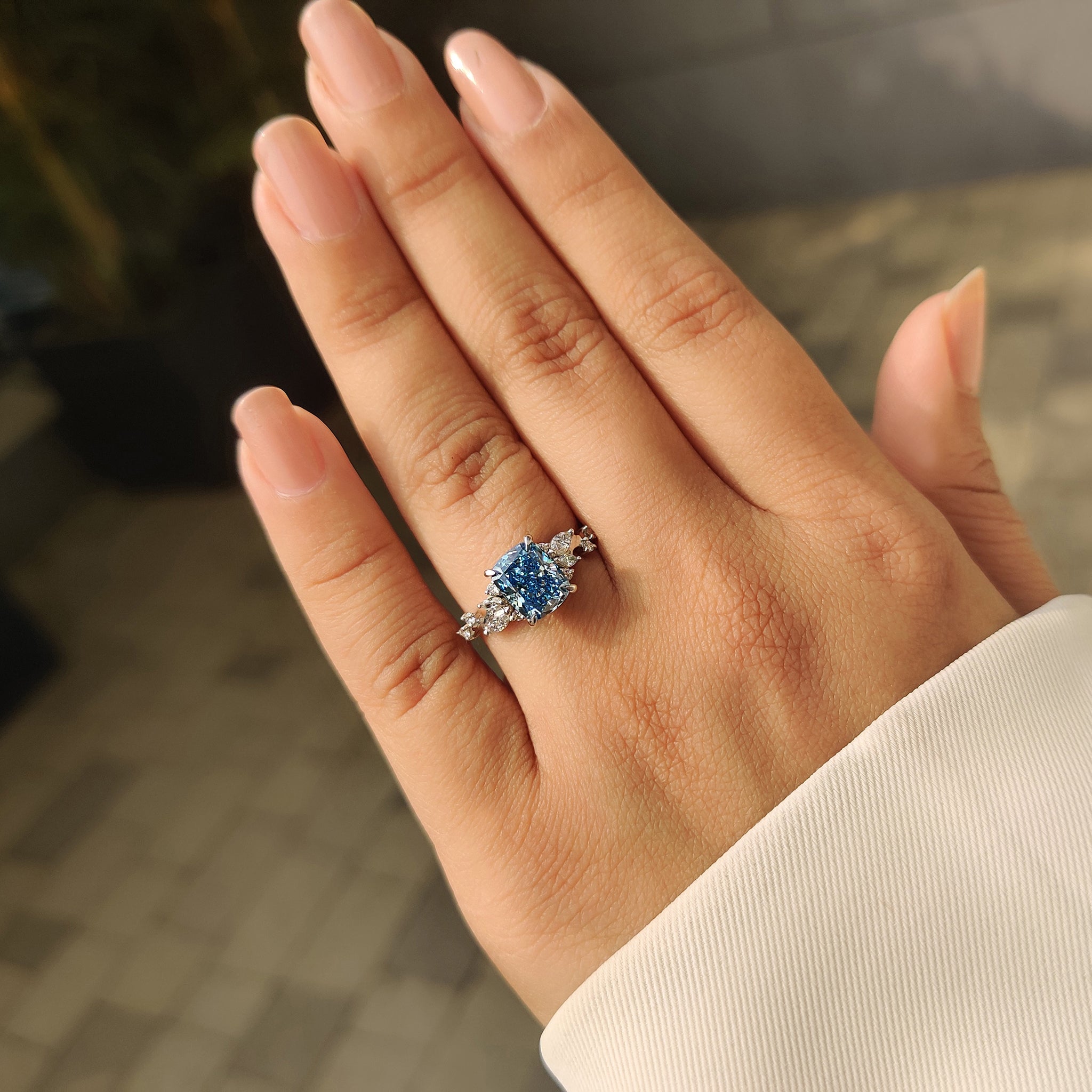 Cushion cut blue diamond ring with marquise and round accent stones.

