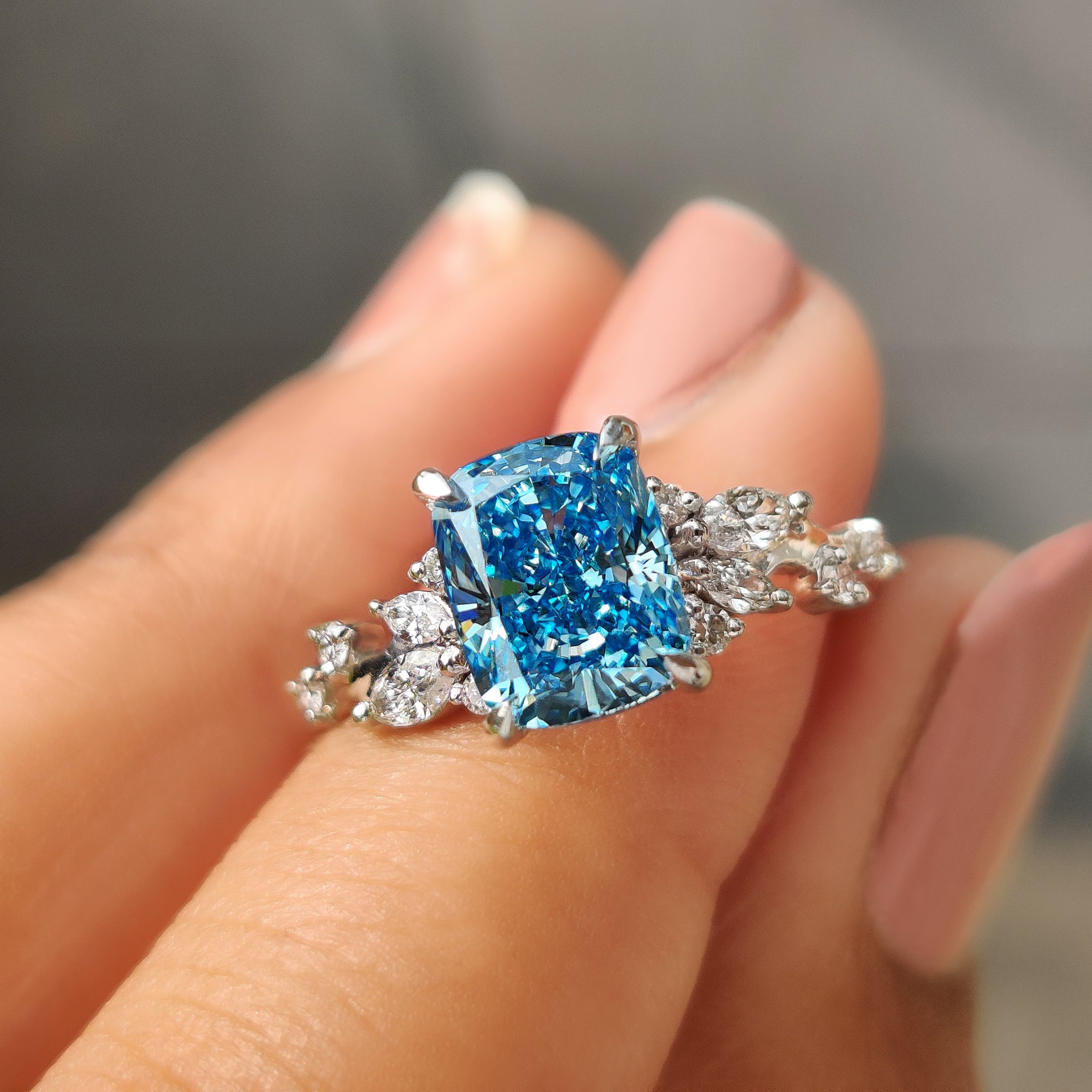 Cushion cut blue diamond ring with marquise side stone details.
