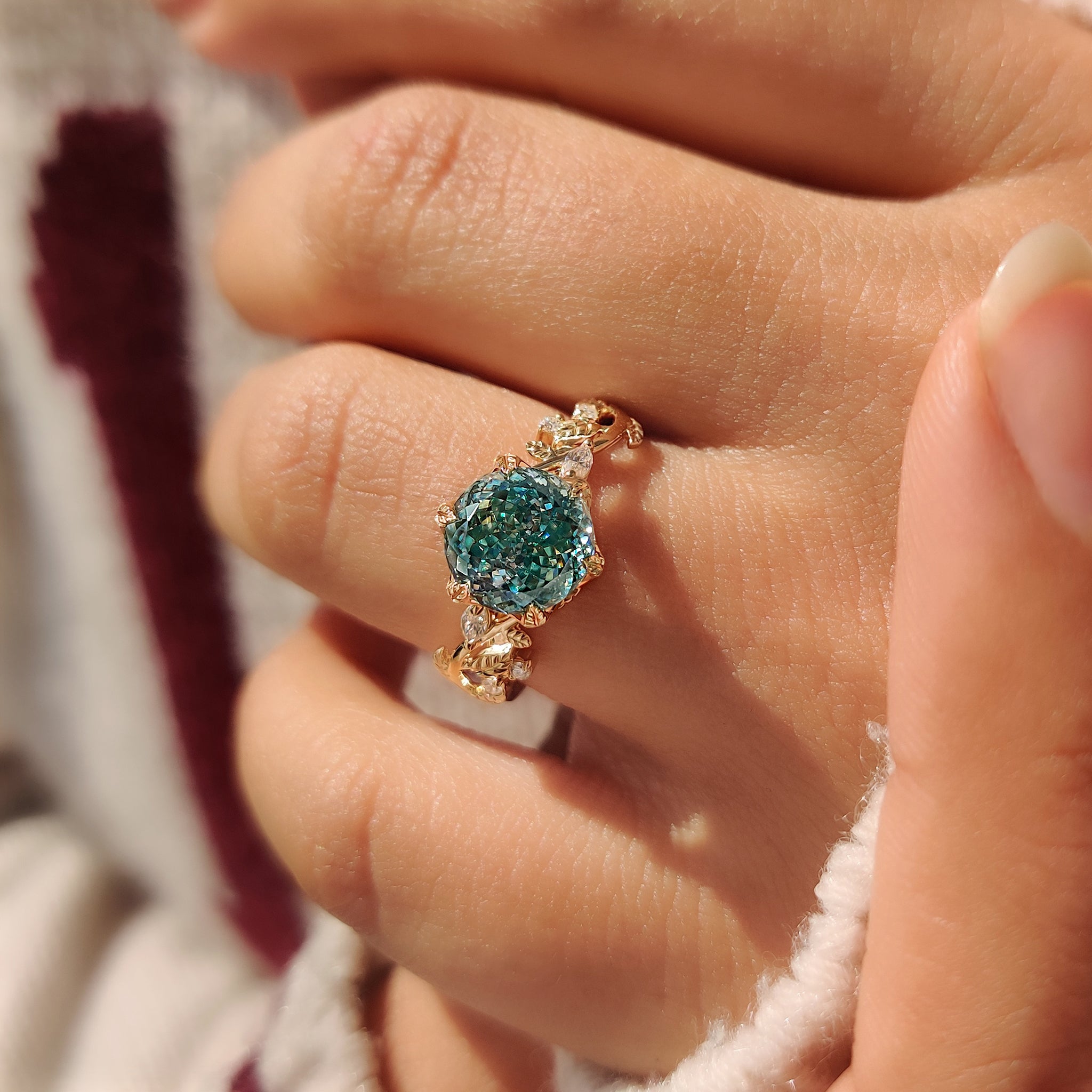 Portuguese cut moissanite ring in cyan blue with leaf design.
