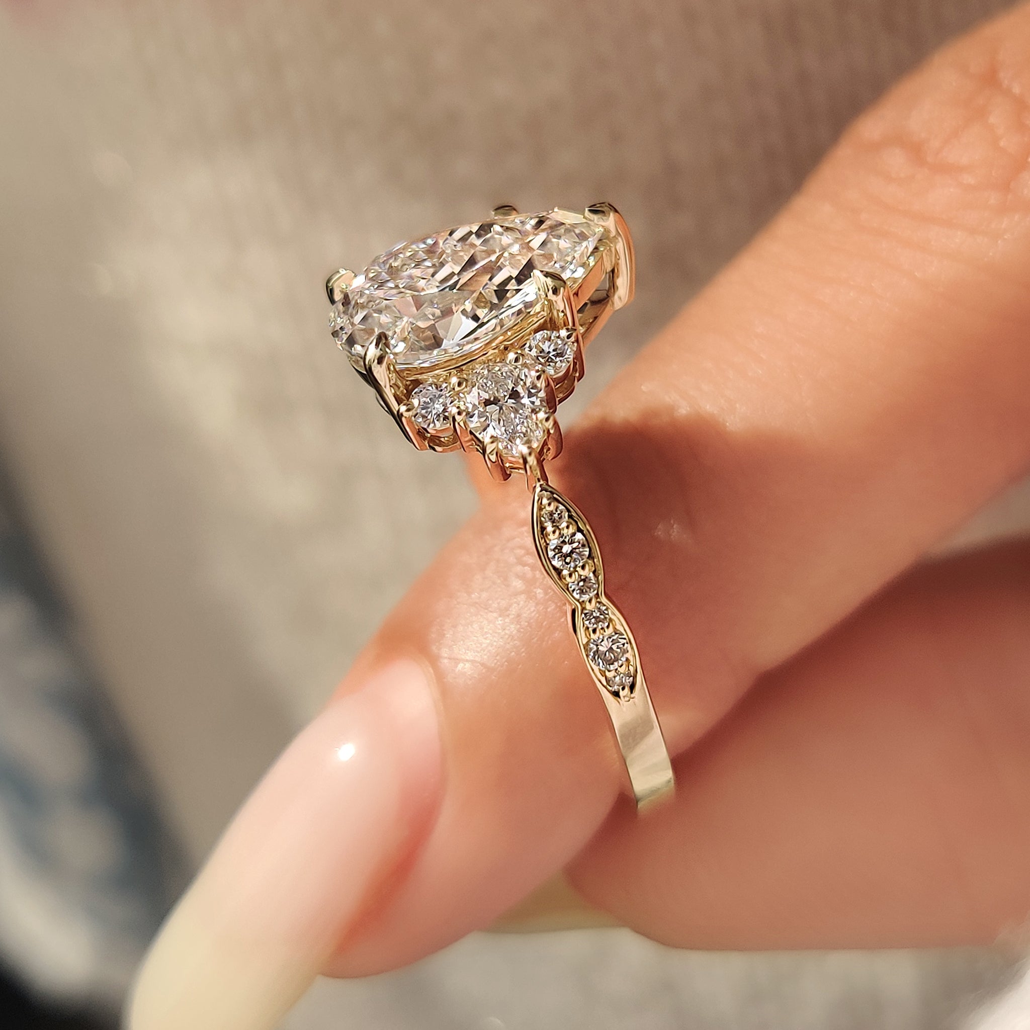 Pear cut ring with side stones and prong set.
