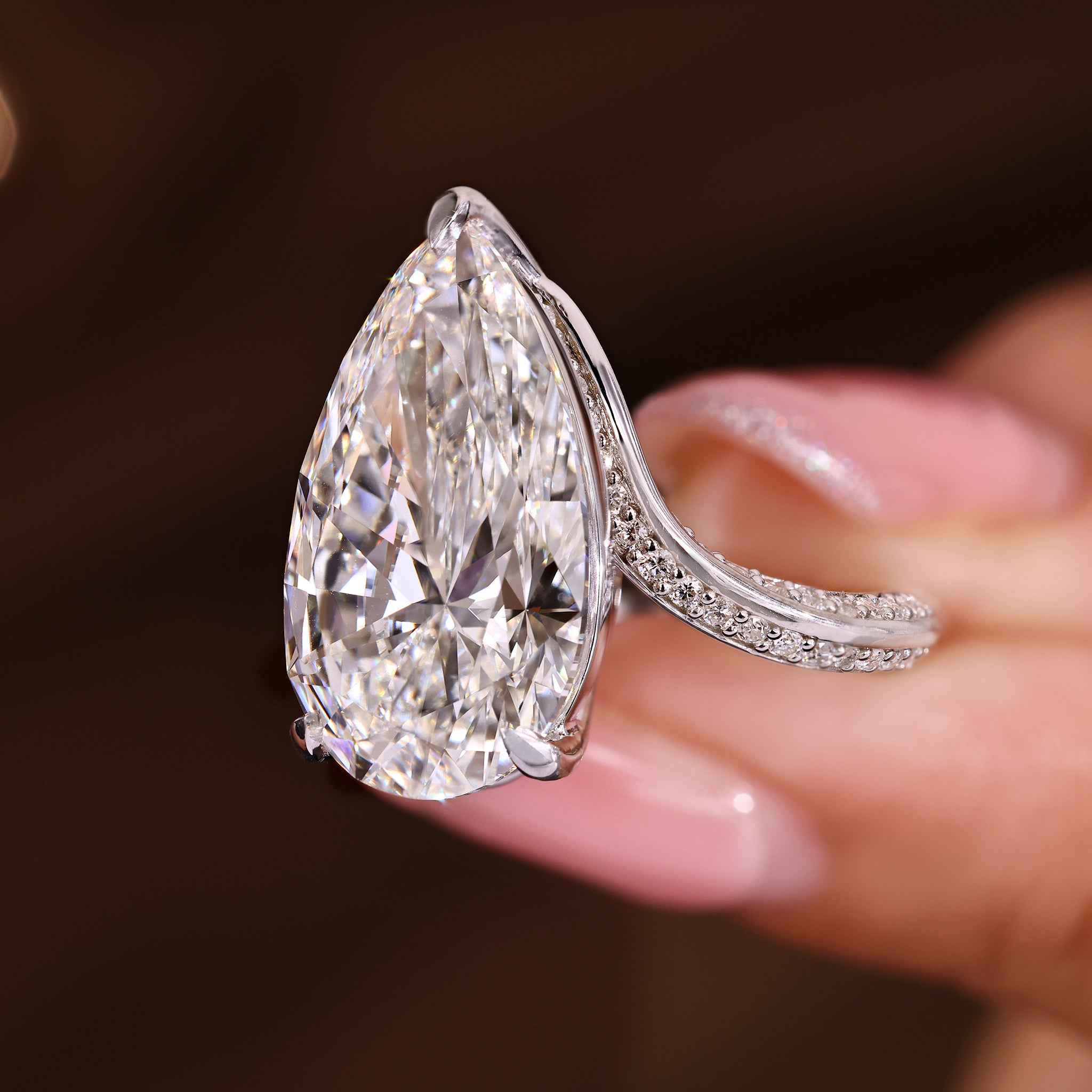 Elegant pear diamond ring by Carat Diamonds with round pave and bypass setting.
