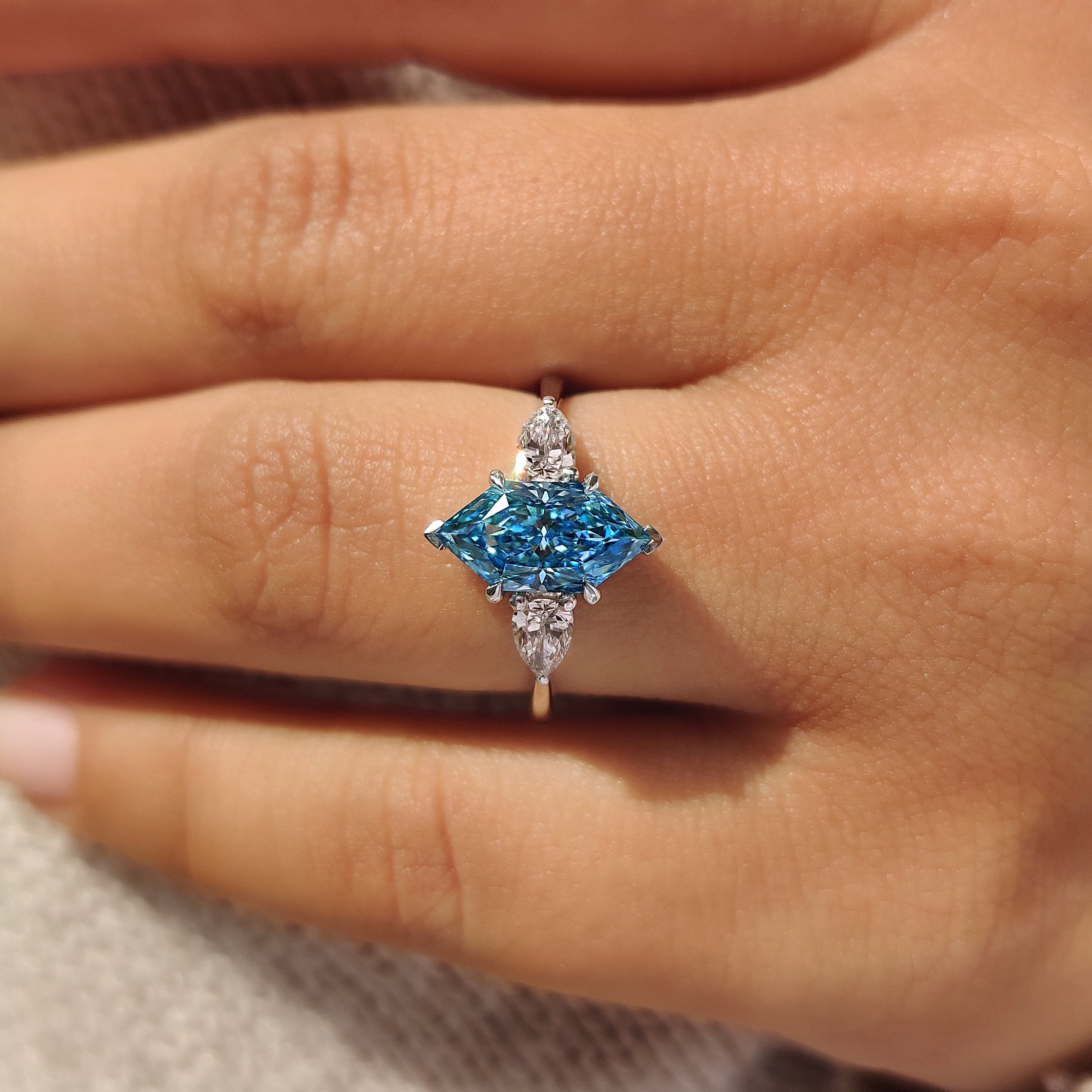 V shape and four claw prong setting securing three stone ring
