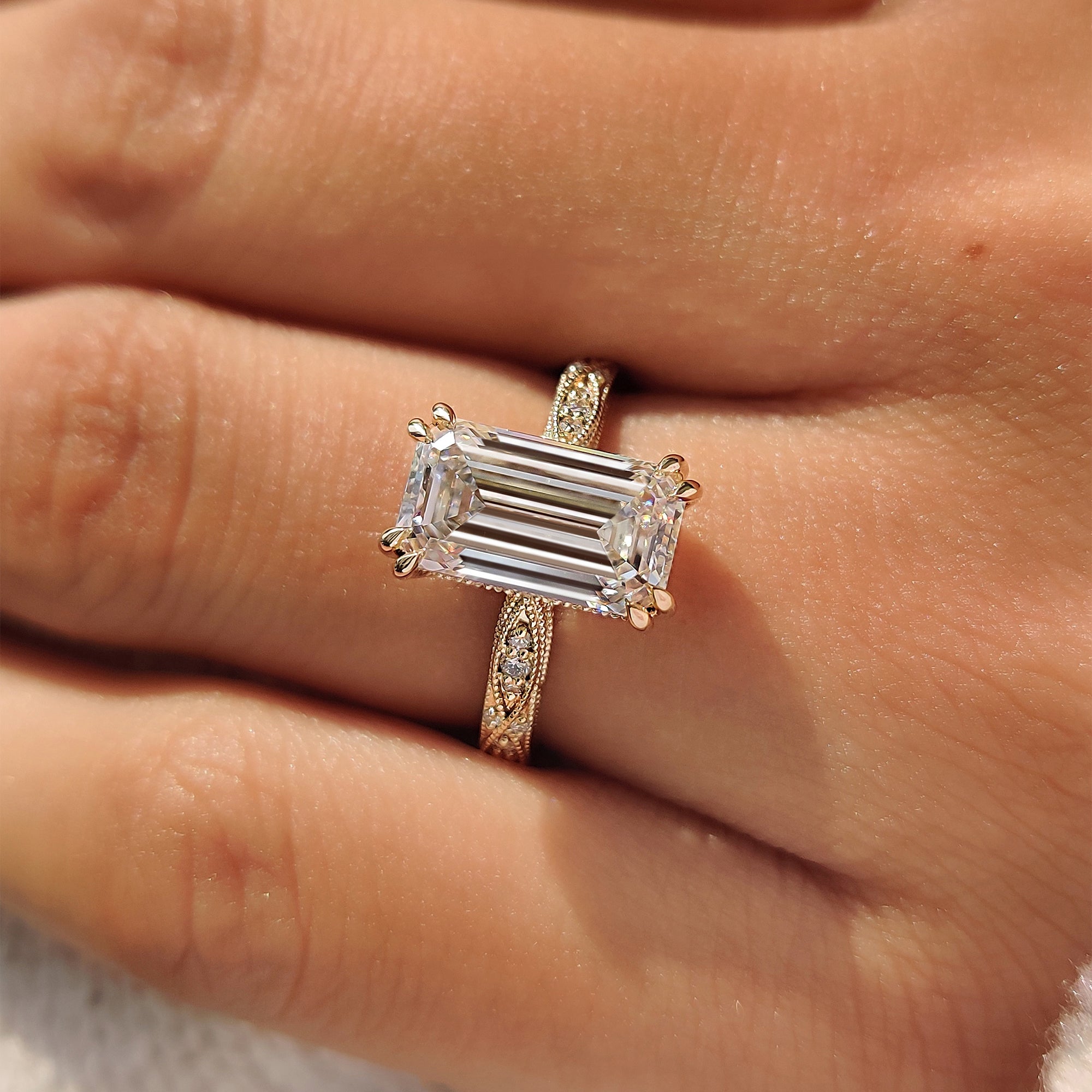 Emerald cut ring with filigree design and milgrain detailing.
