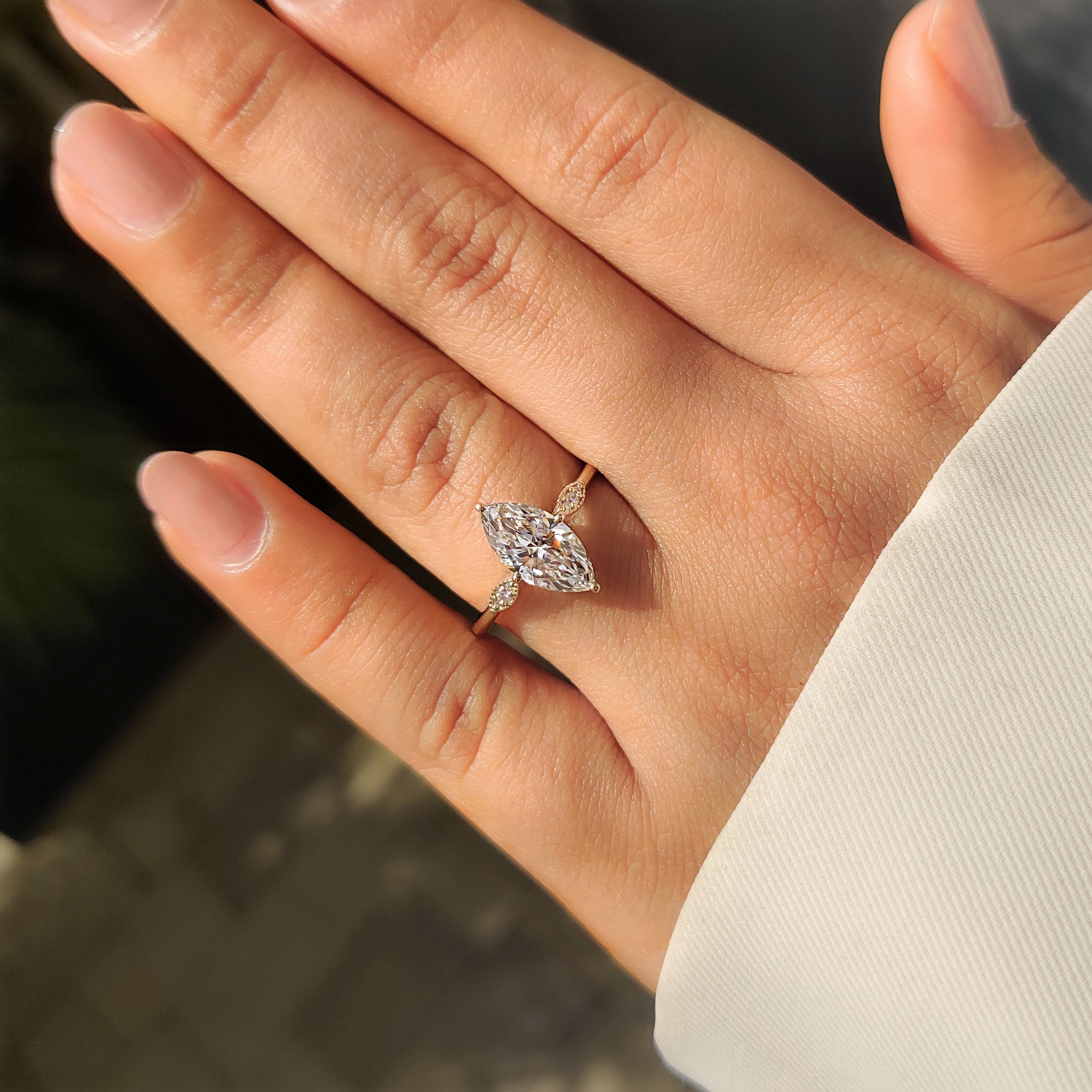 Marquise diamond ring featuring round stones and compass setting.

