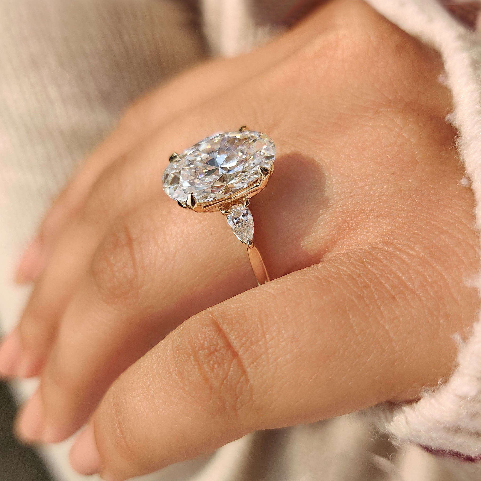 Oval diamond engagement ring with pear side stone details
