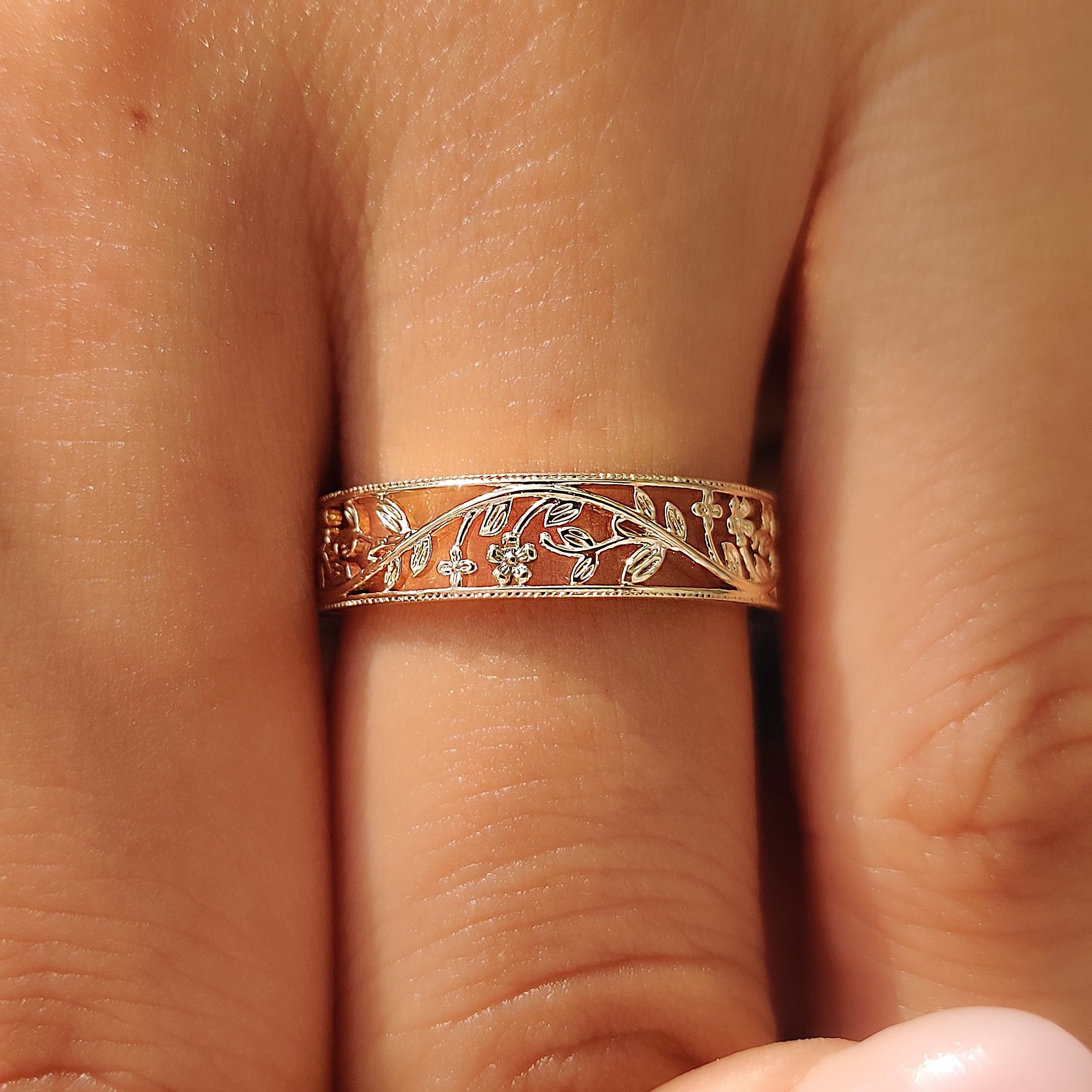 Cherry blossom flower motifs across an openwork wedding band.
