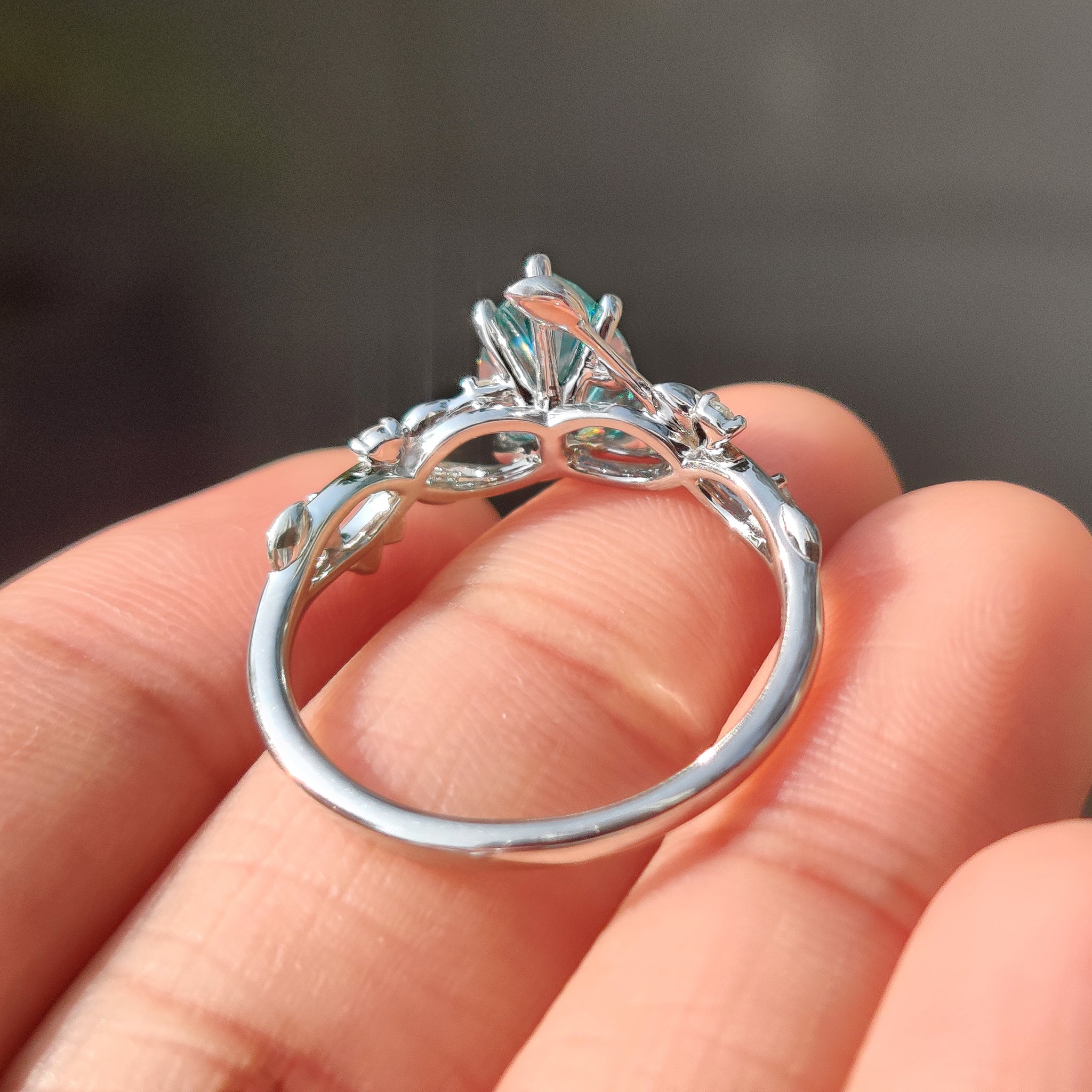 Pear moissanite ring with round side stones and prongs
