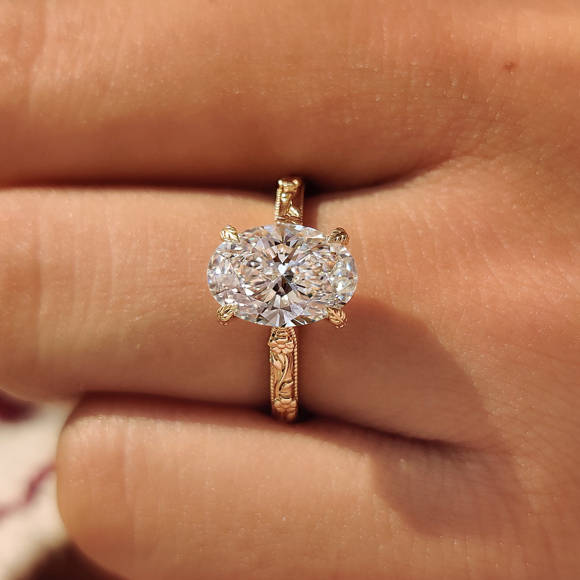 Four leaf style prongs securing oval center diamond.
