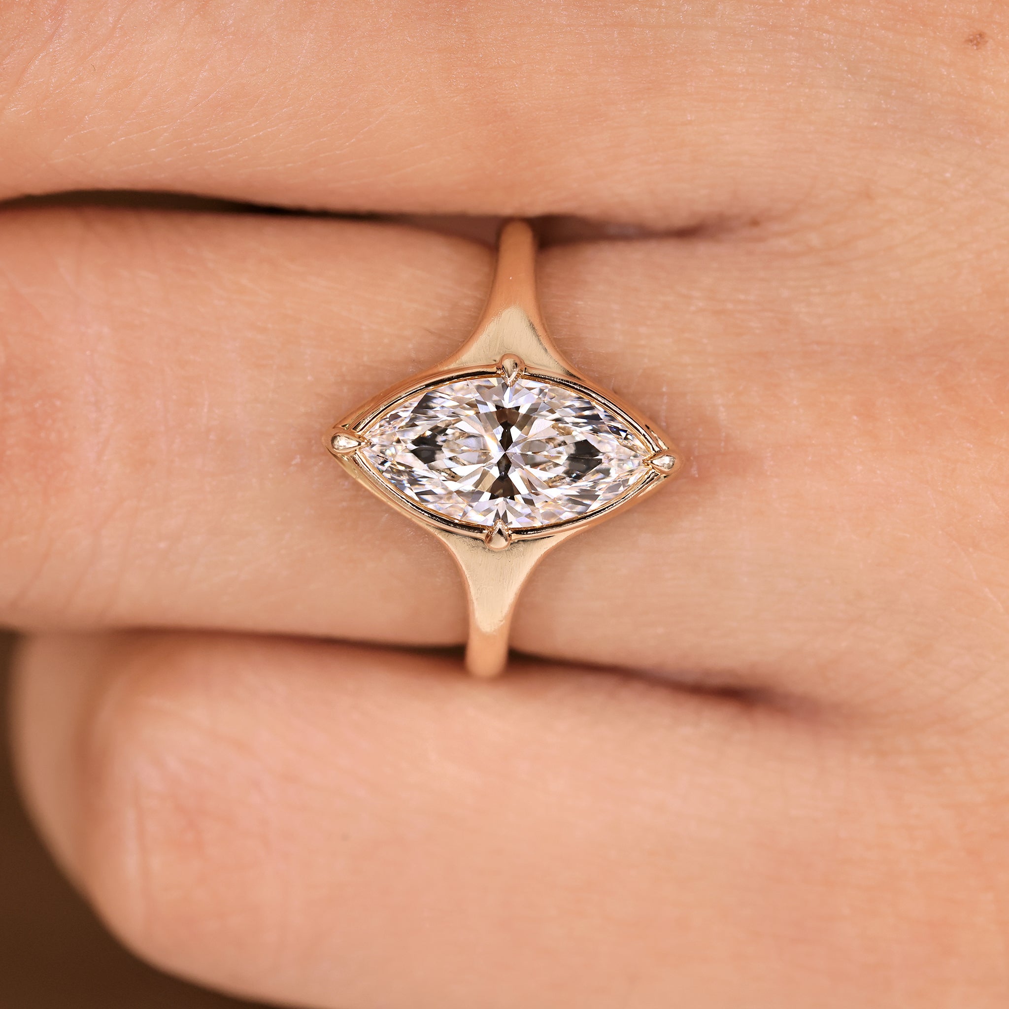 Tapered shank marquise cut engagement ring with bezel setting.

