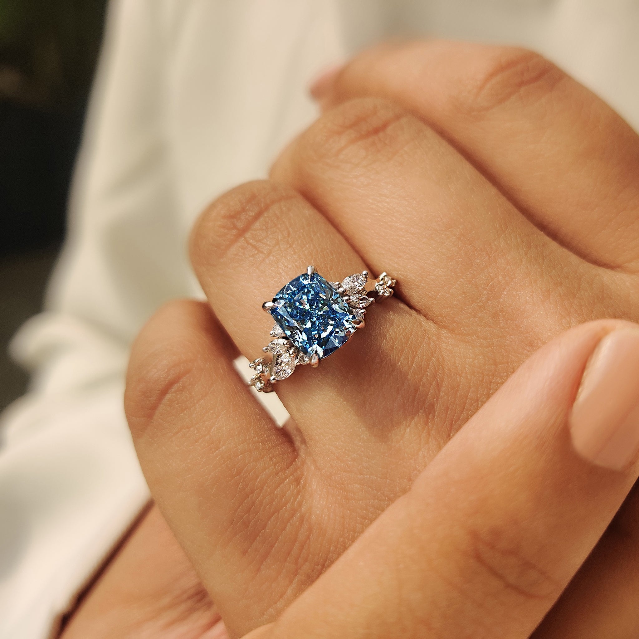 Handmade cushion cut diamond ring with blue diamond and side stones.
