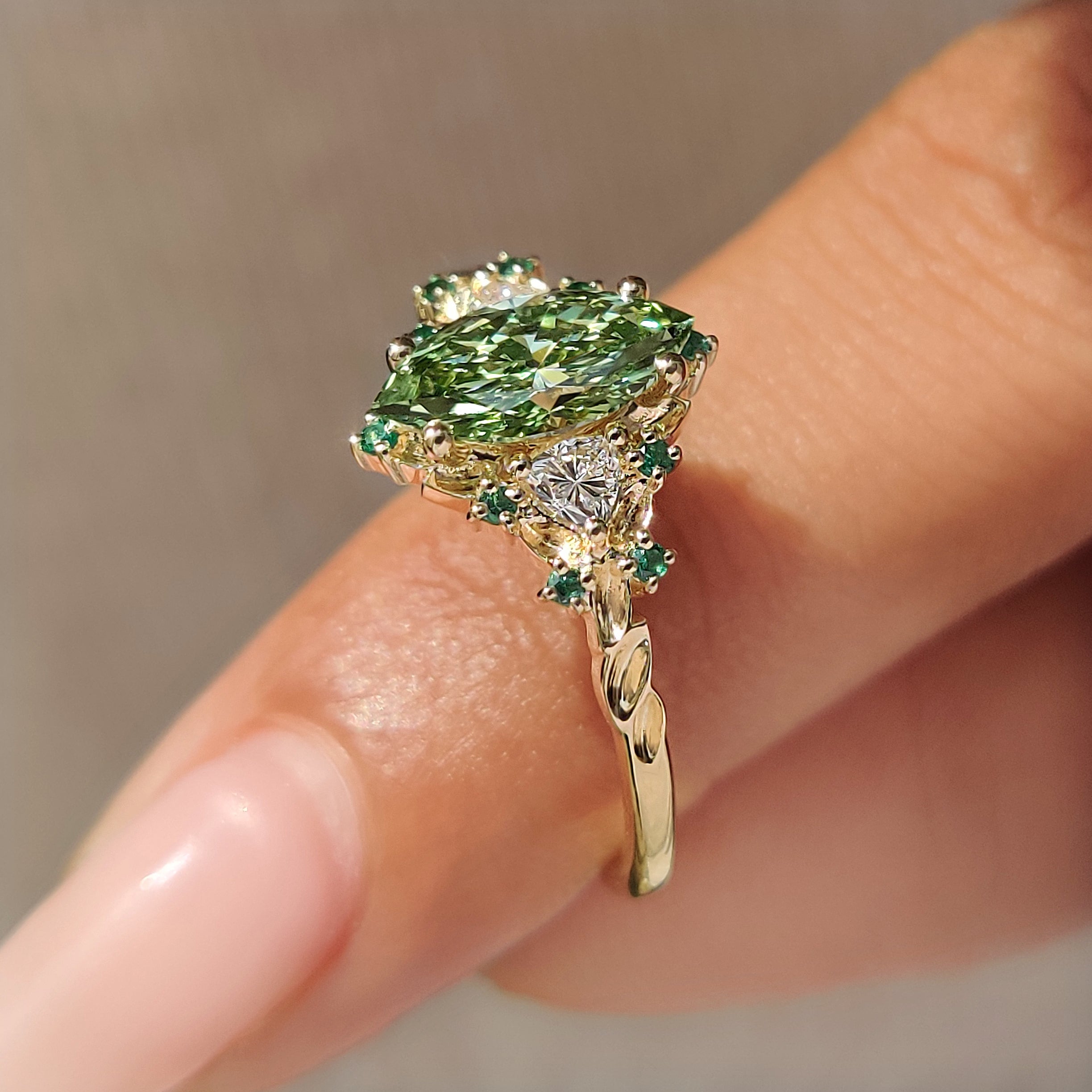 Green emerald round accents on marquise cluster ring.
