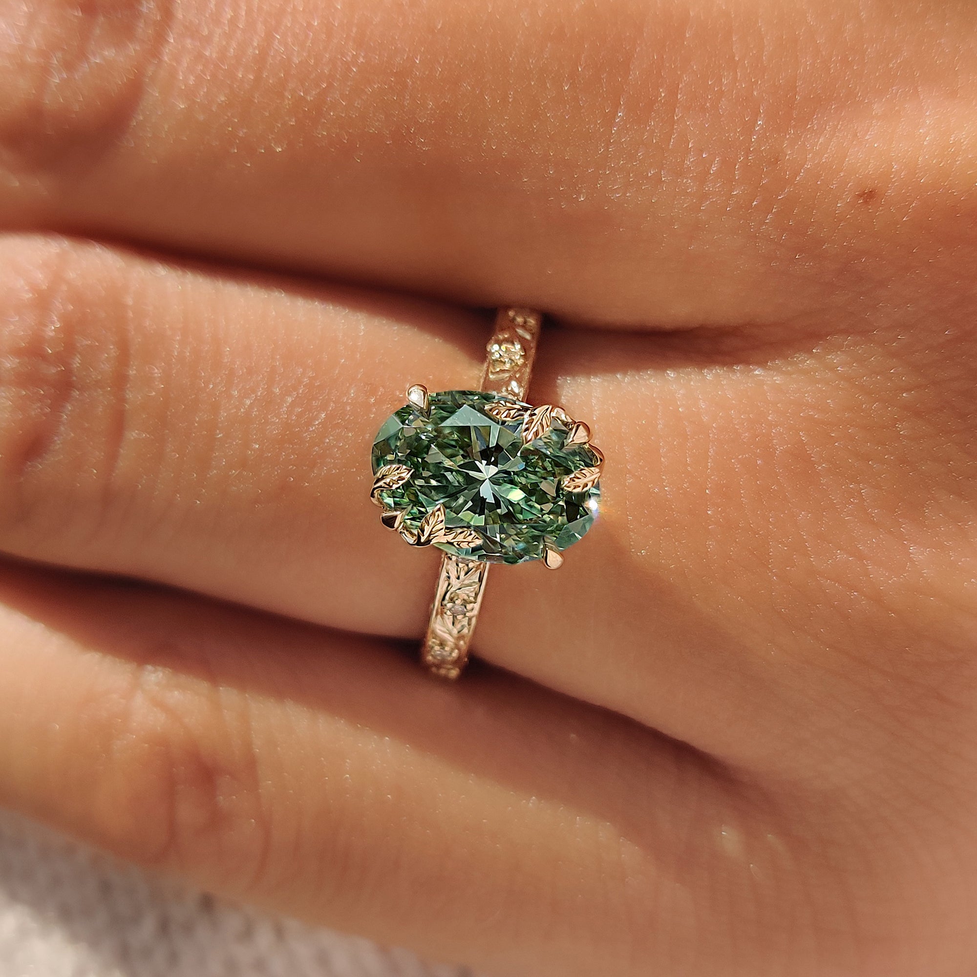 Green oval engagement ring with tulip setting.
