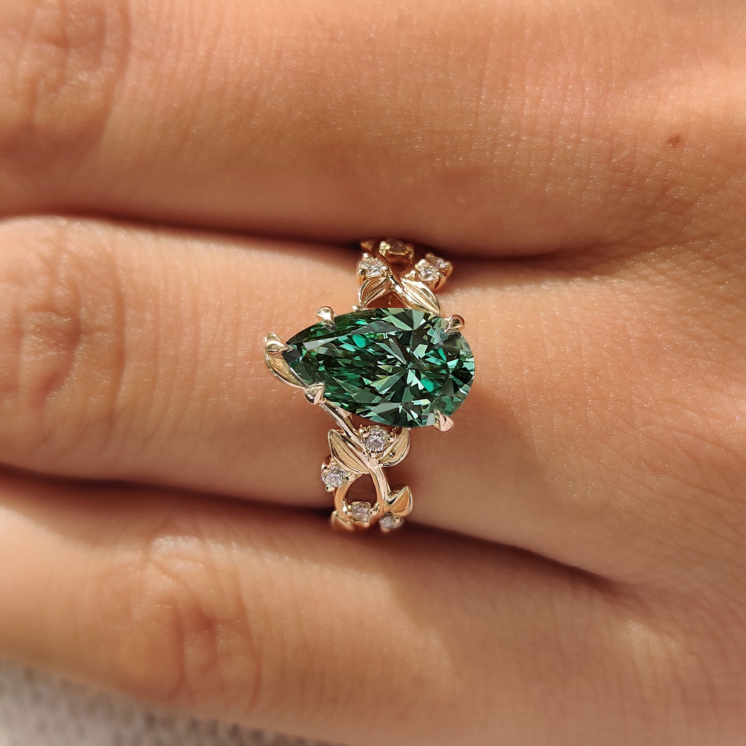 Green pear shaped diamond with leaves and petals design.
