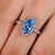 Blue center marquise diamond ring with round halo stones
