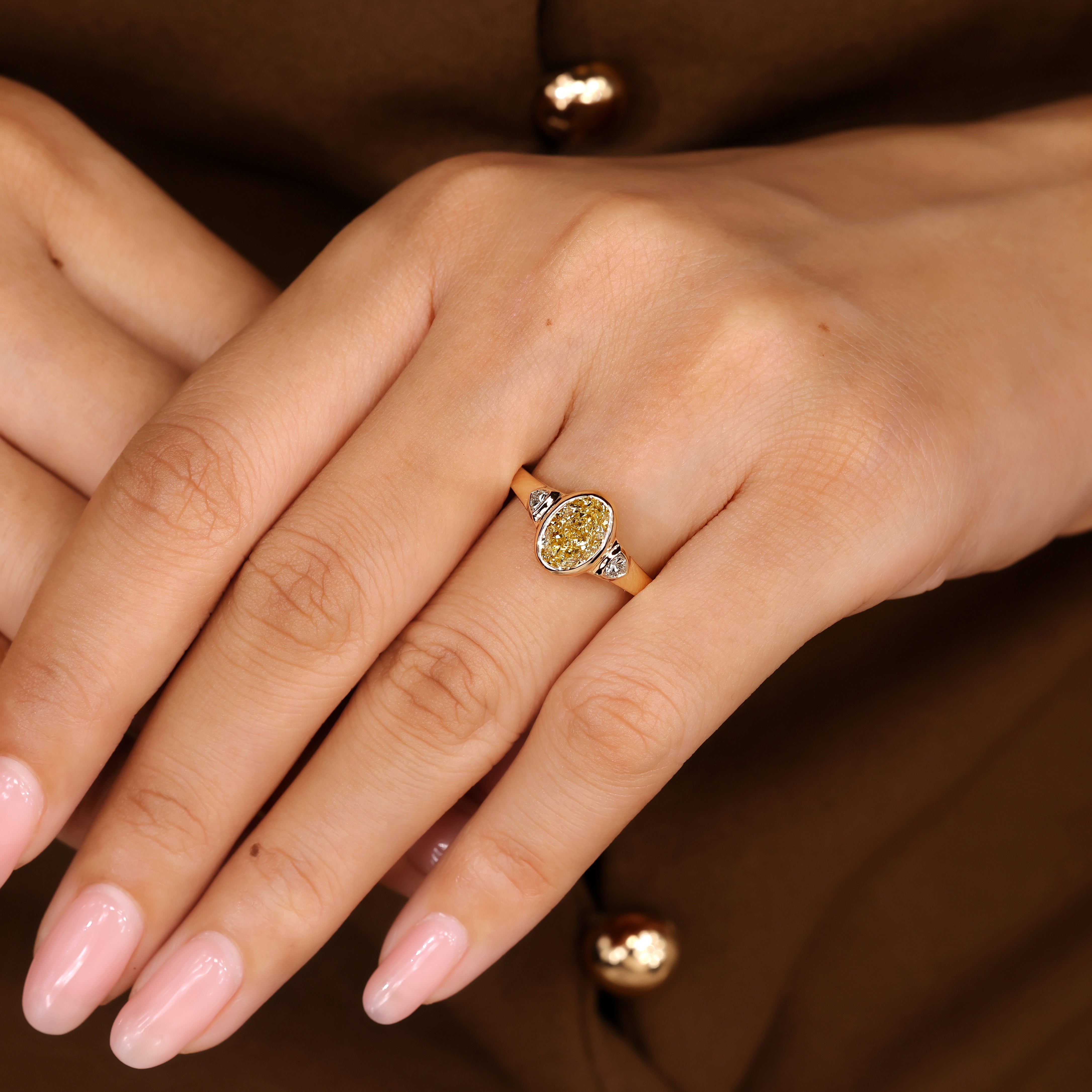 Cathedral style oval diamond ring with bezel setting details
