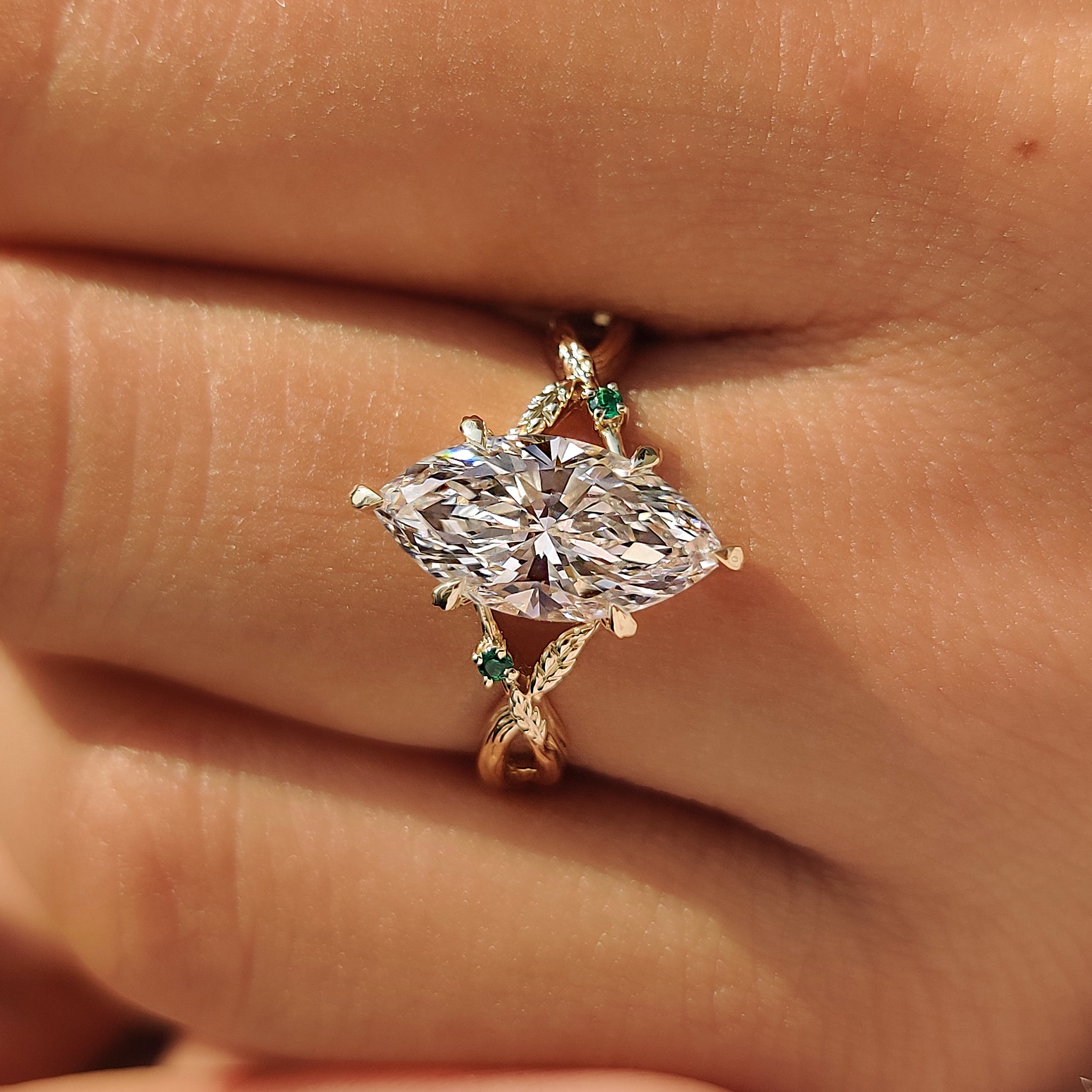 Marquise lab grown diamond with green emerald accents.
