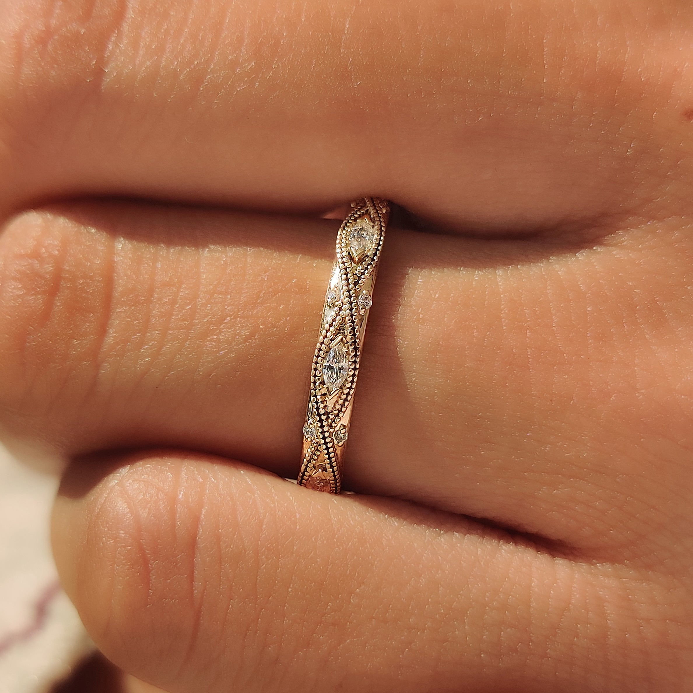 Round and marquise lab grown diamonds across a wedding band.
