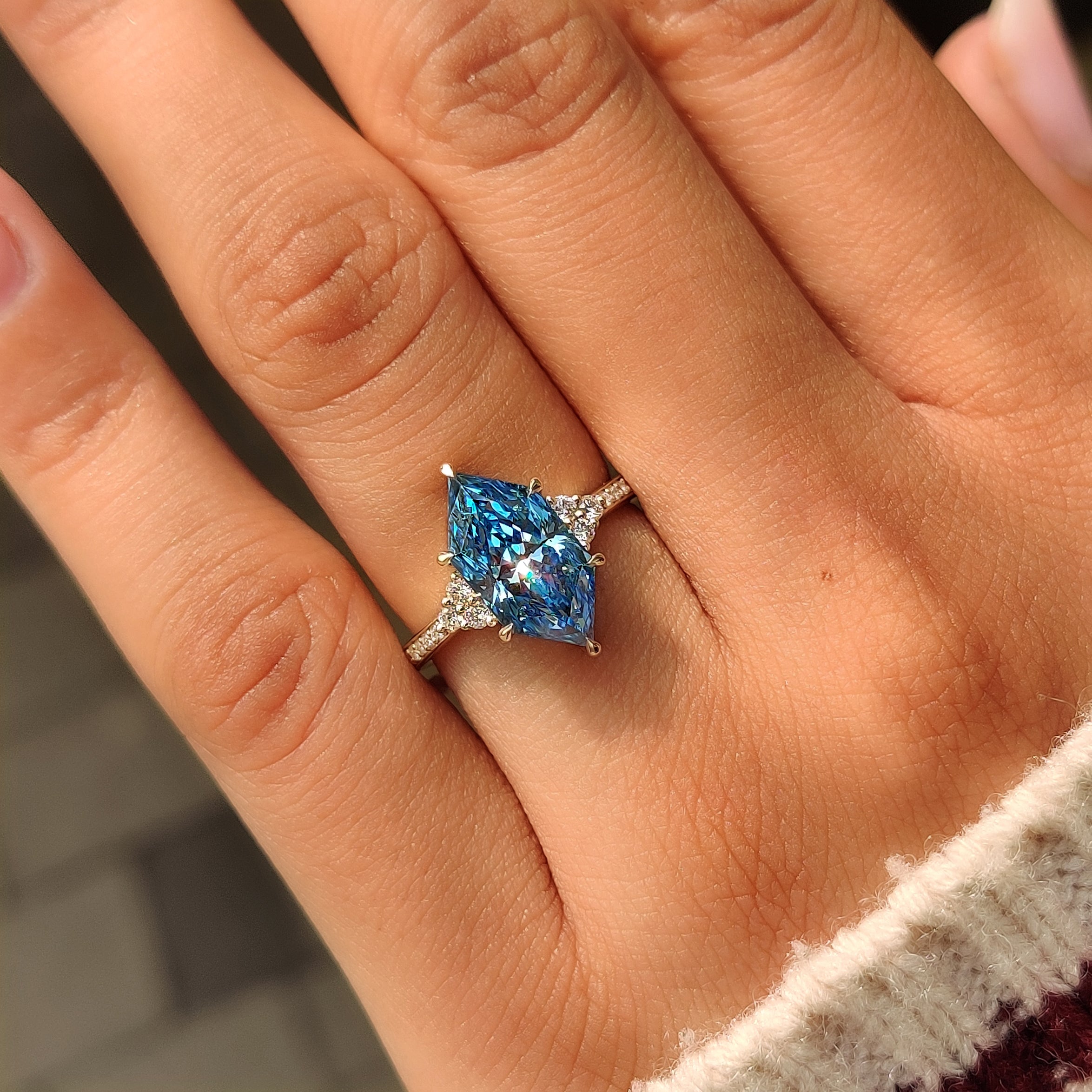 Round side stones set around a blue Dutch marquise diamond.
