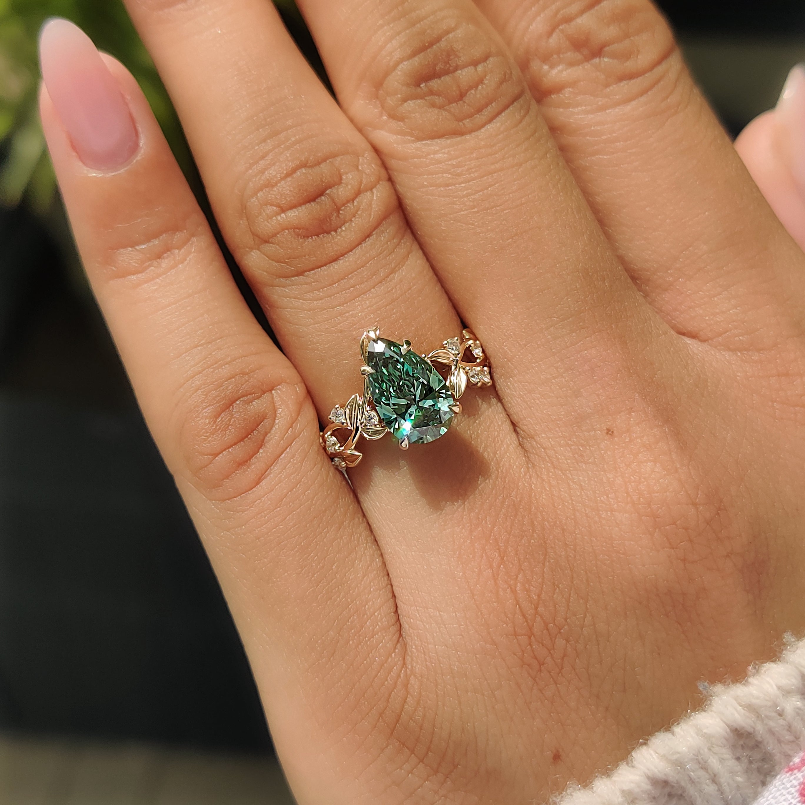 Green pear shaped diamond with five claw prong.
