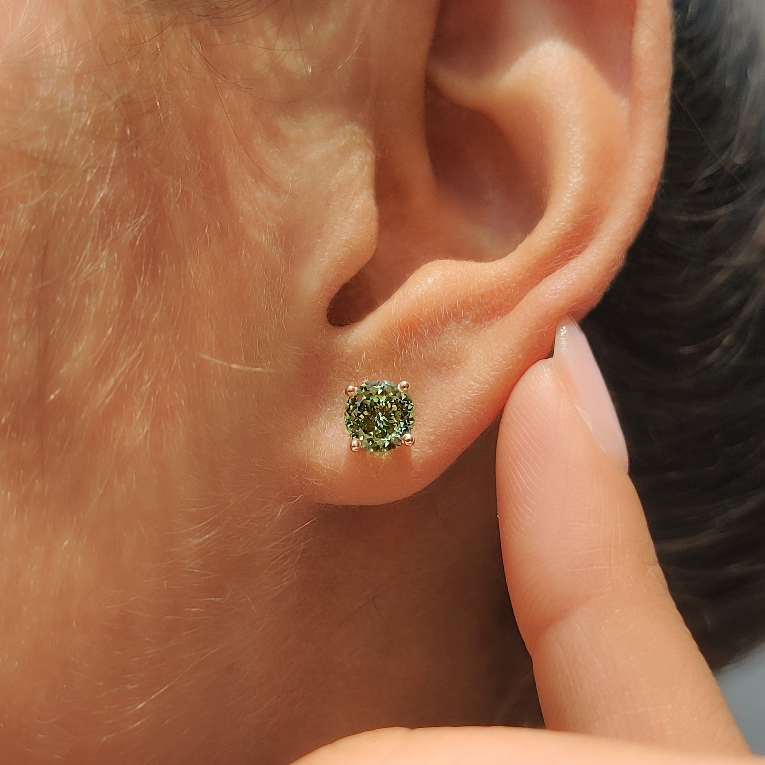 Green diamond stud earrings with secure four prong setting
