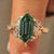 Green hexagon step cut diamond cluster ring with leaf engraving.
