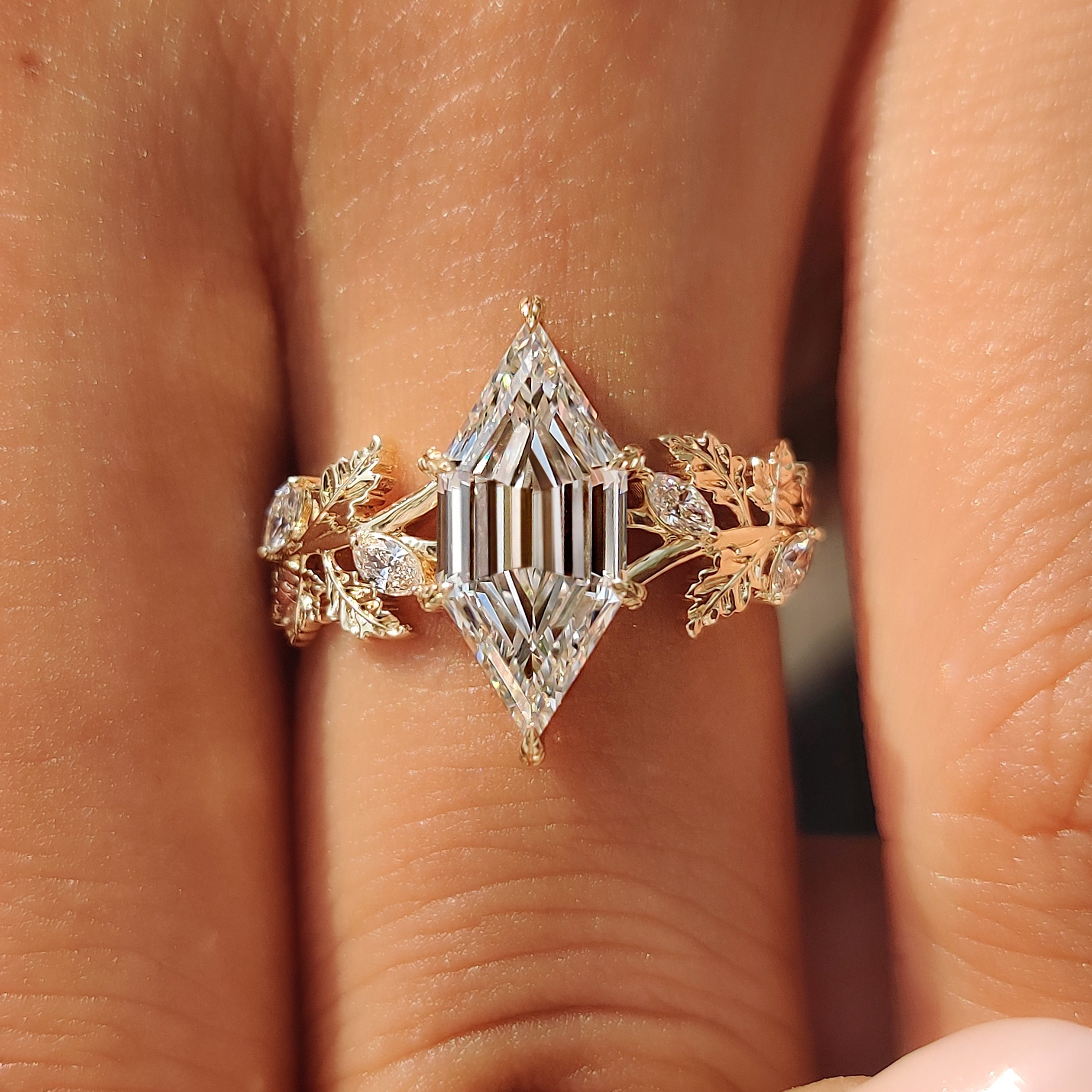 Six leaf style prongs holding the lab grown hexagon step cut diamond.
