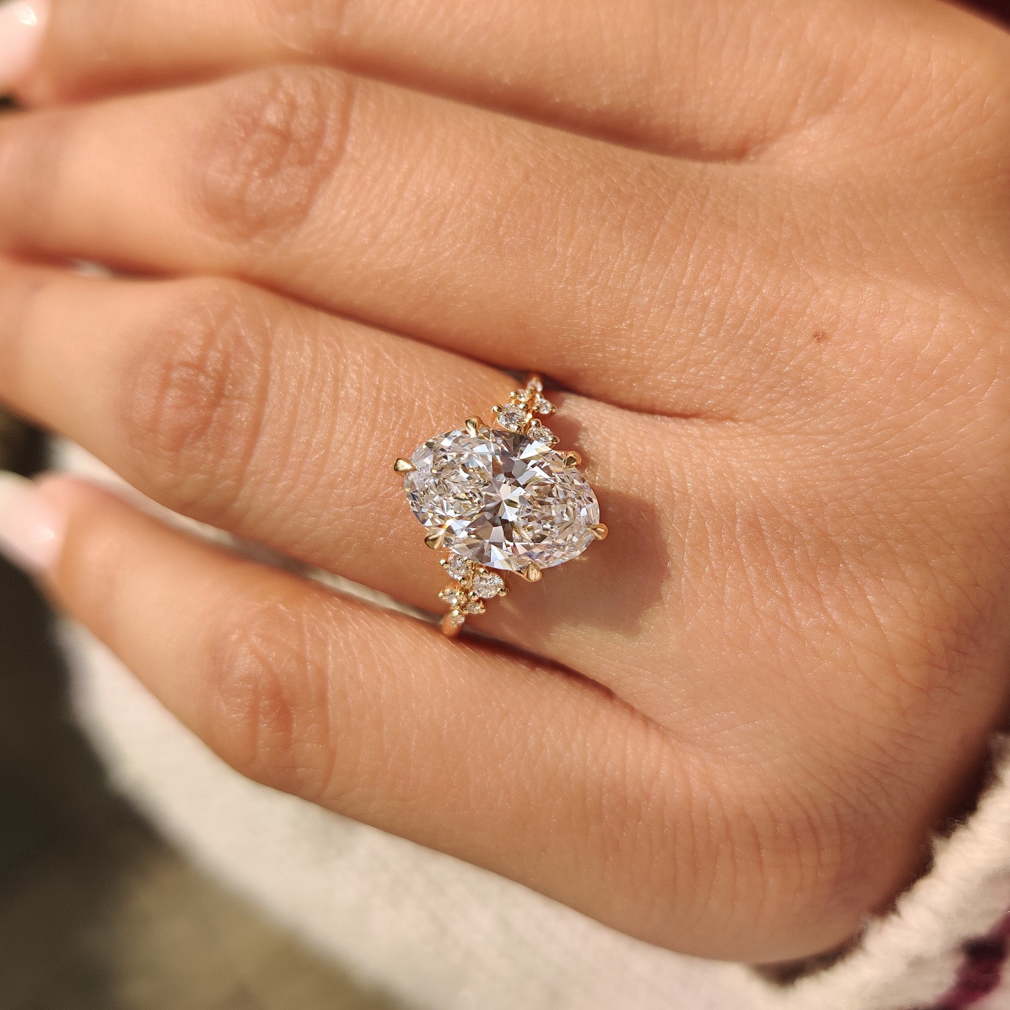 Oval diamond engagement ring with cluster design.
