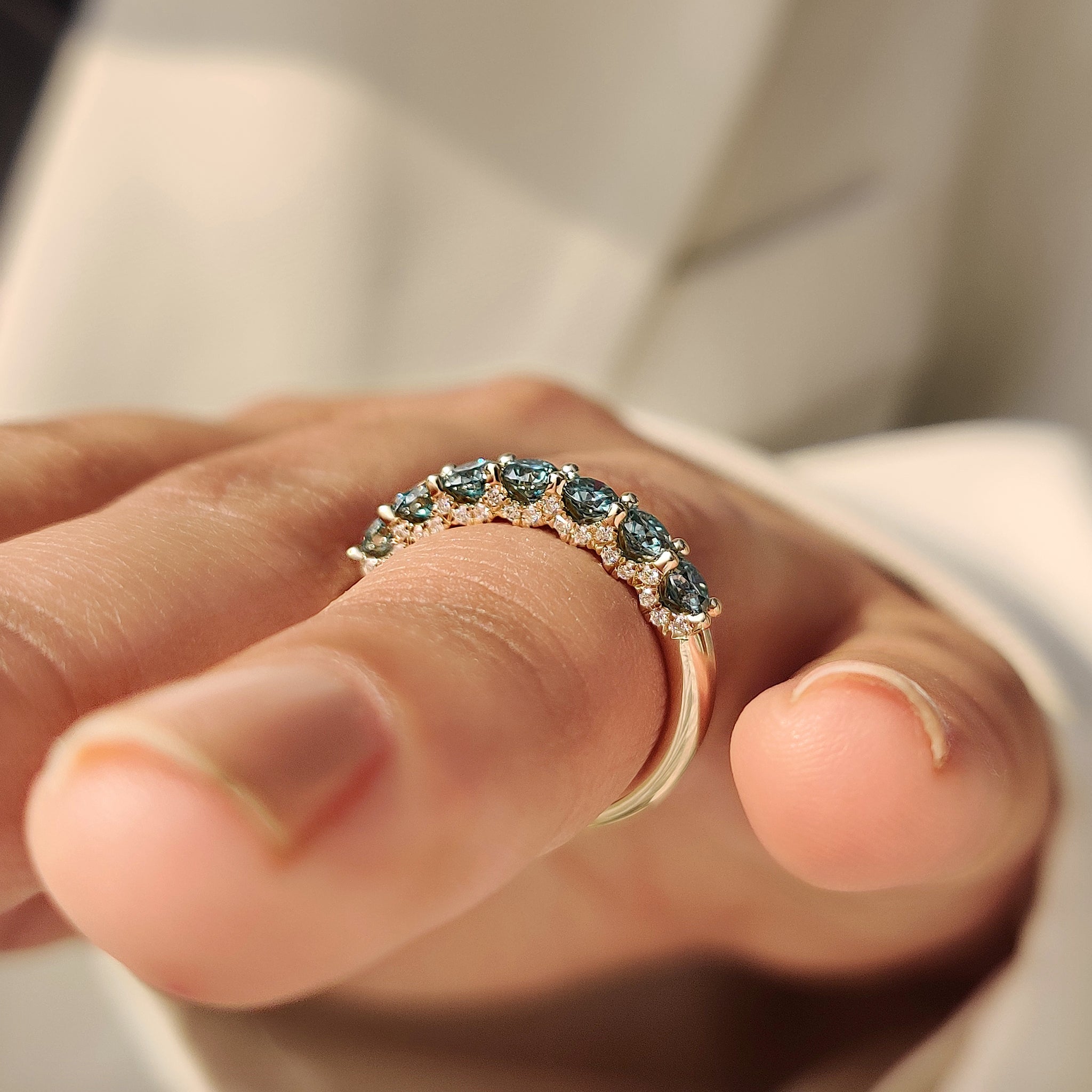 Blue moissanite wedding band with round stones and prongs.
