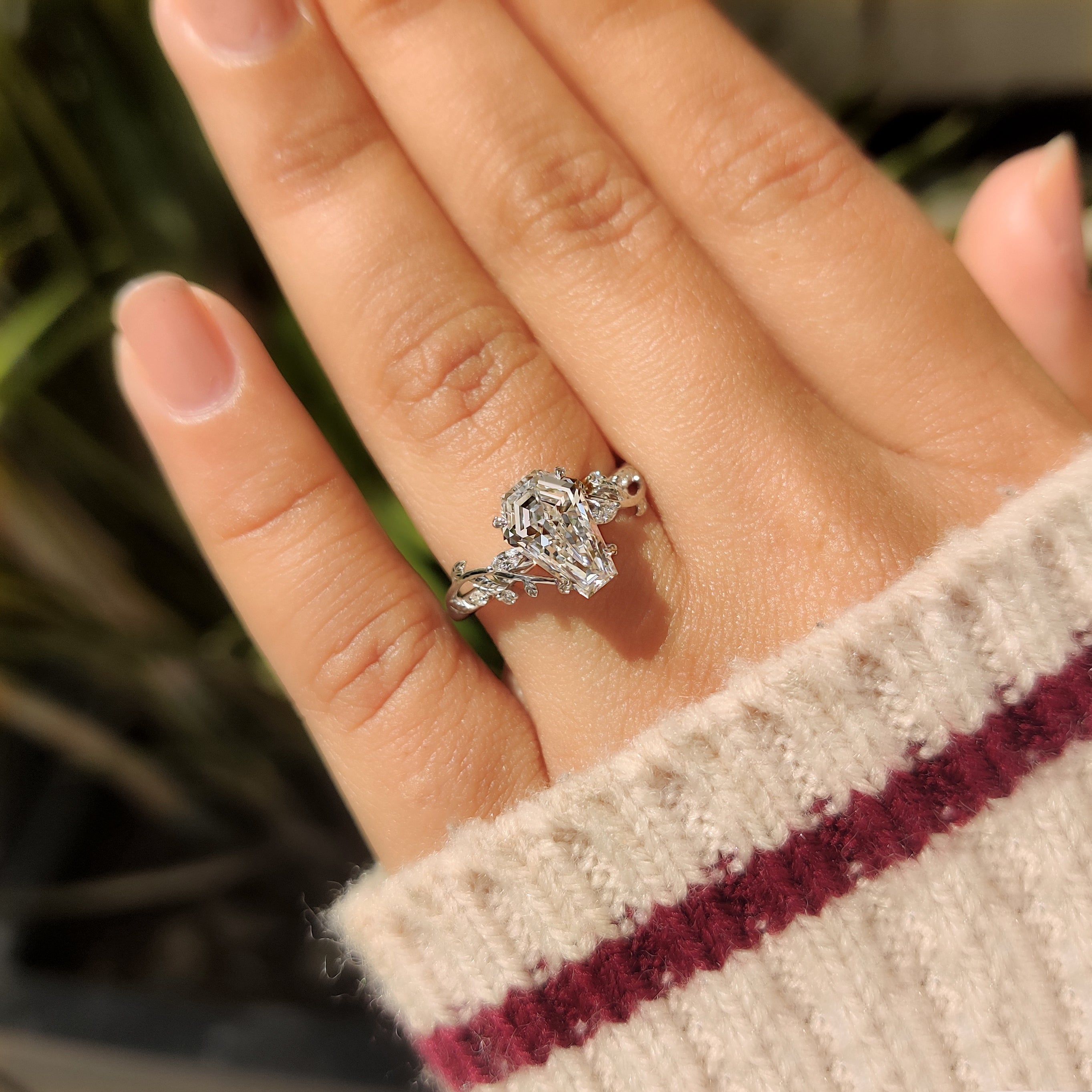 Coffin diamond ring with round stones and leaf prongs.
