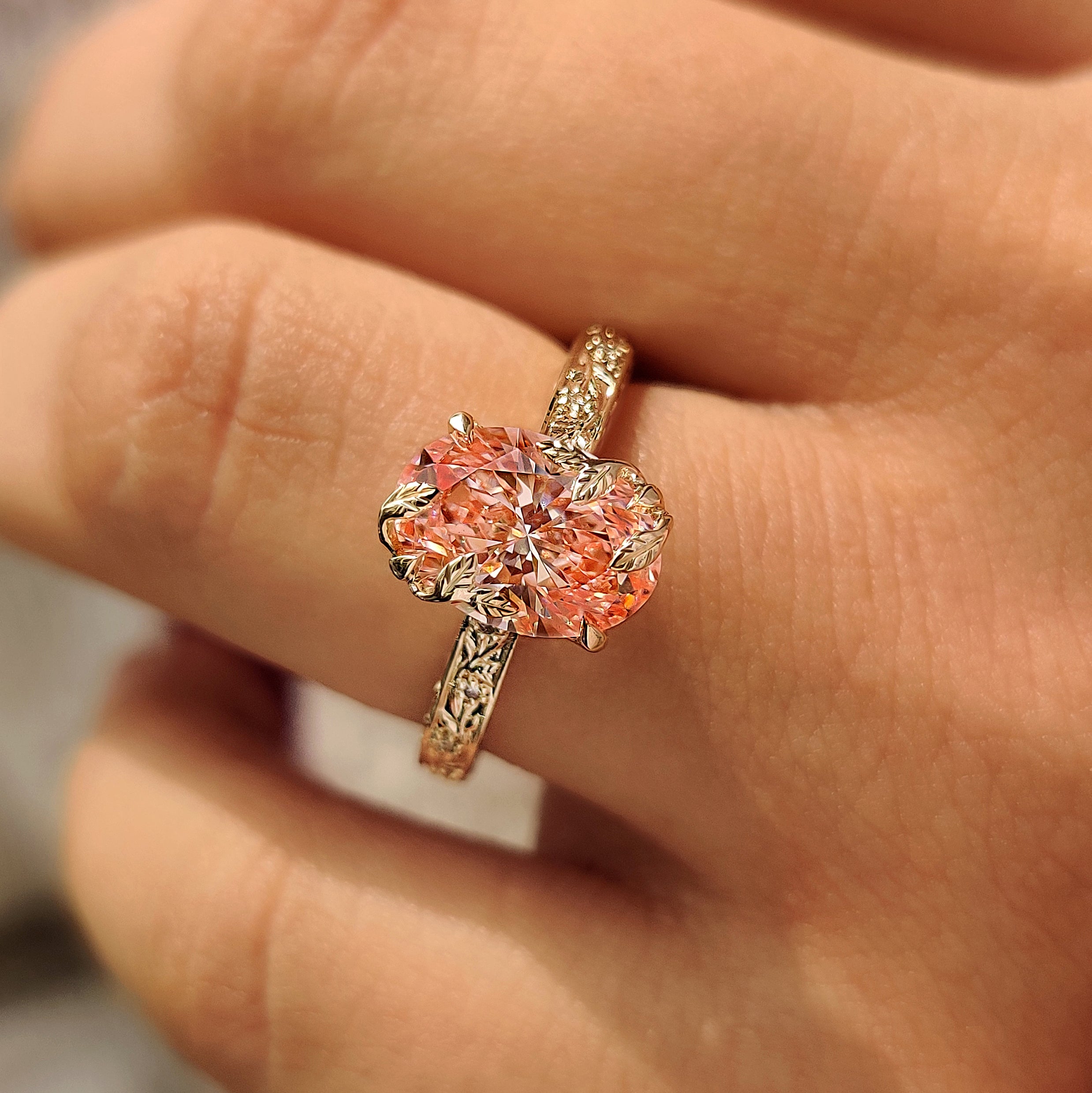 Pink oval shaped ring with four claw prong setting.
