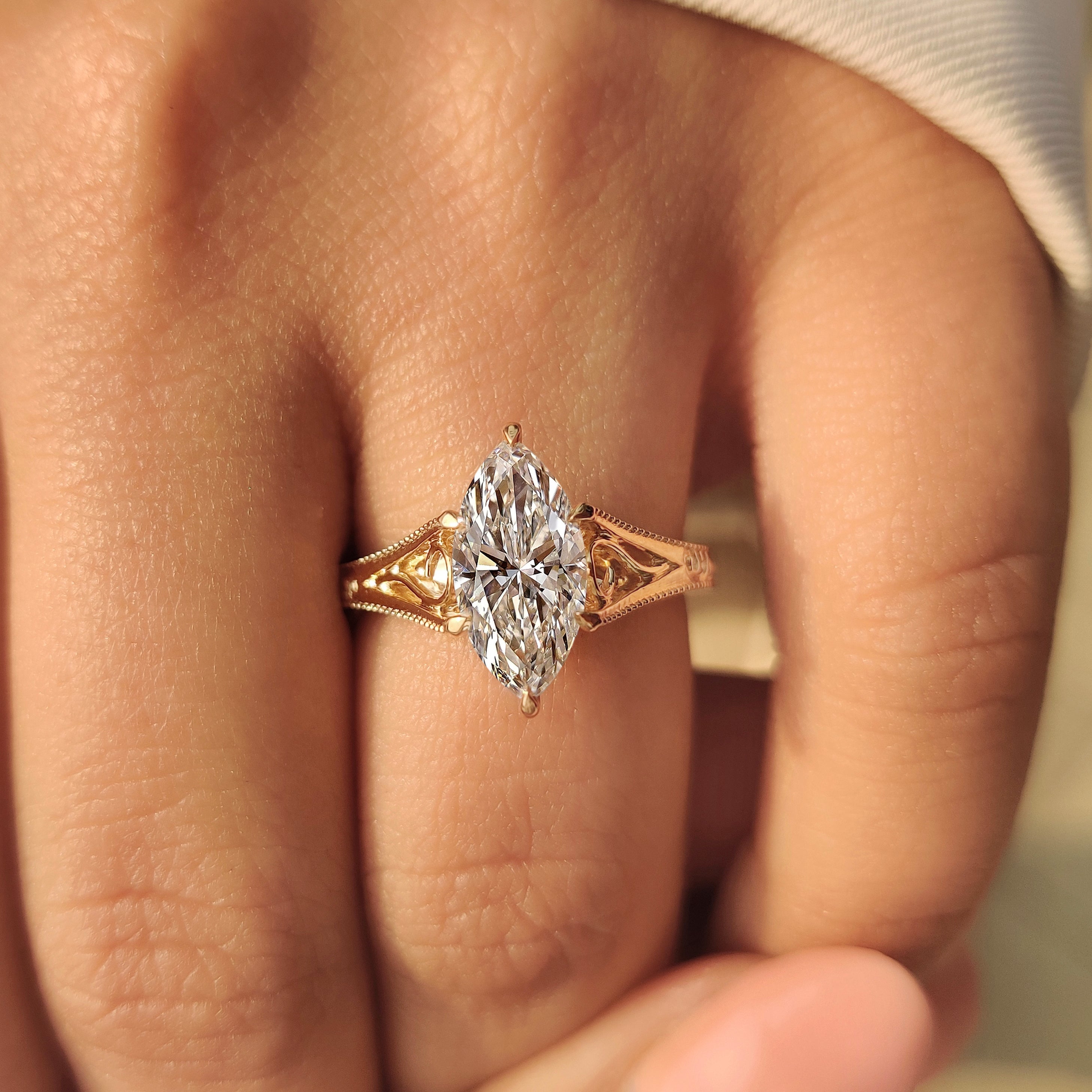 Marquise solitaire diamond ring with detailed vintage style band.
