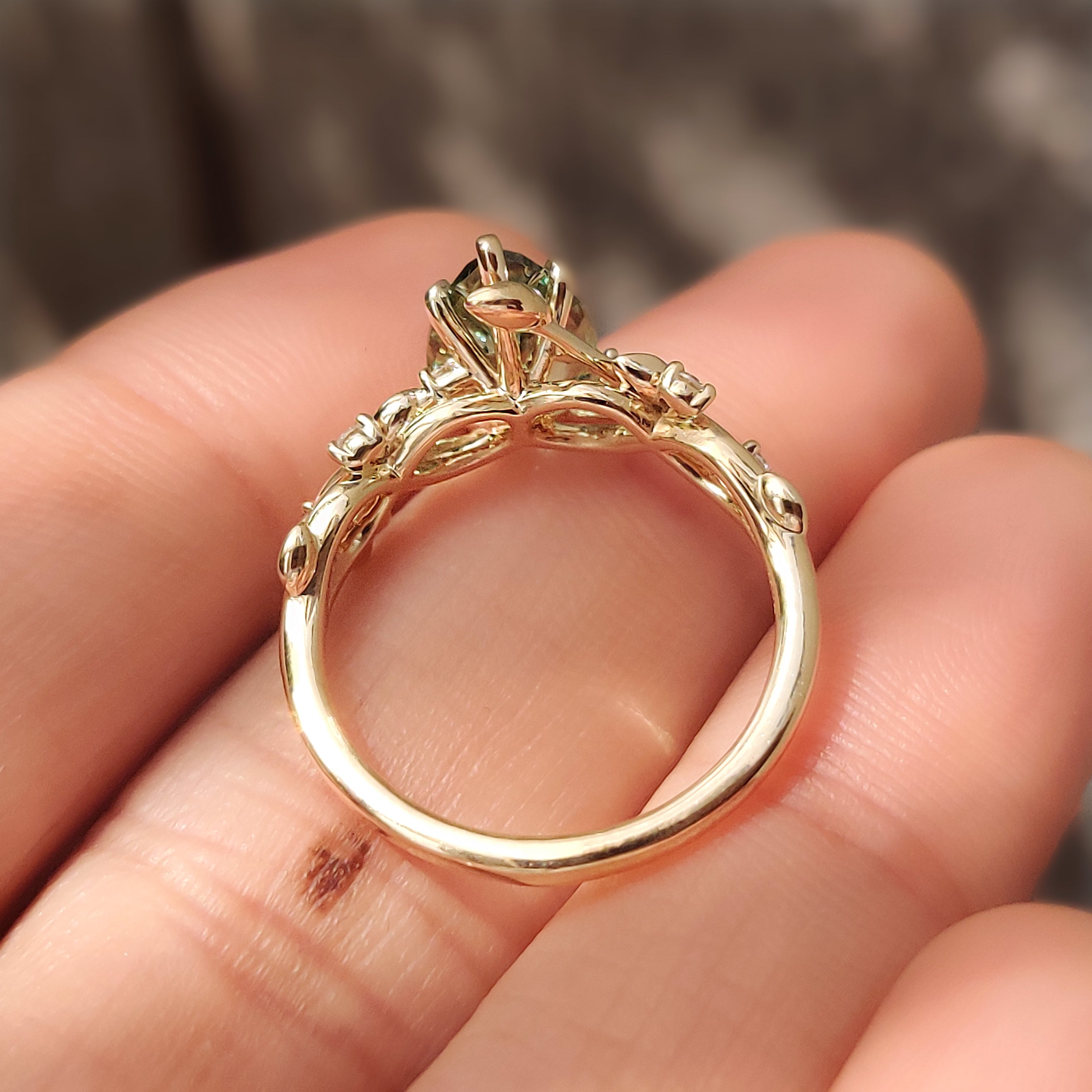 Green pear shaped diamond ring with round side stones.
