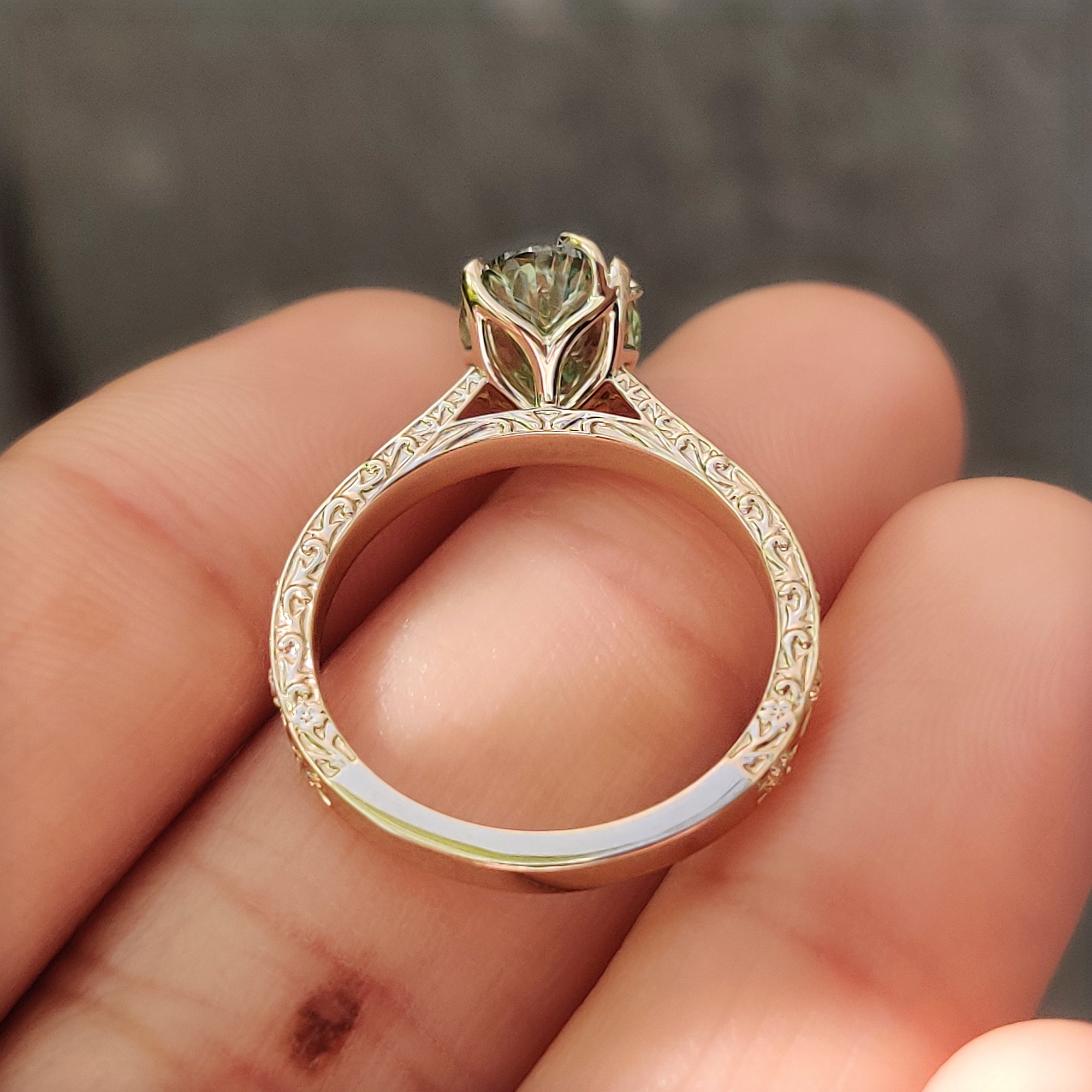 Leaf detailing across a yellow gold oval diamond ring.
