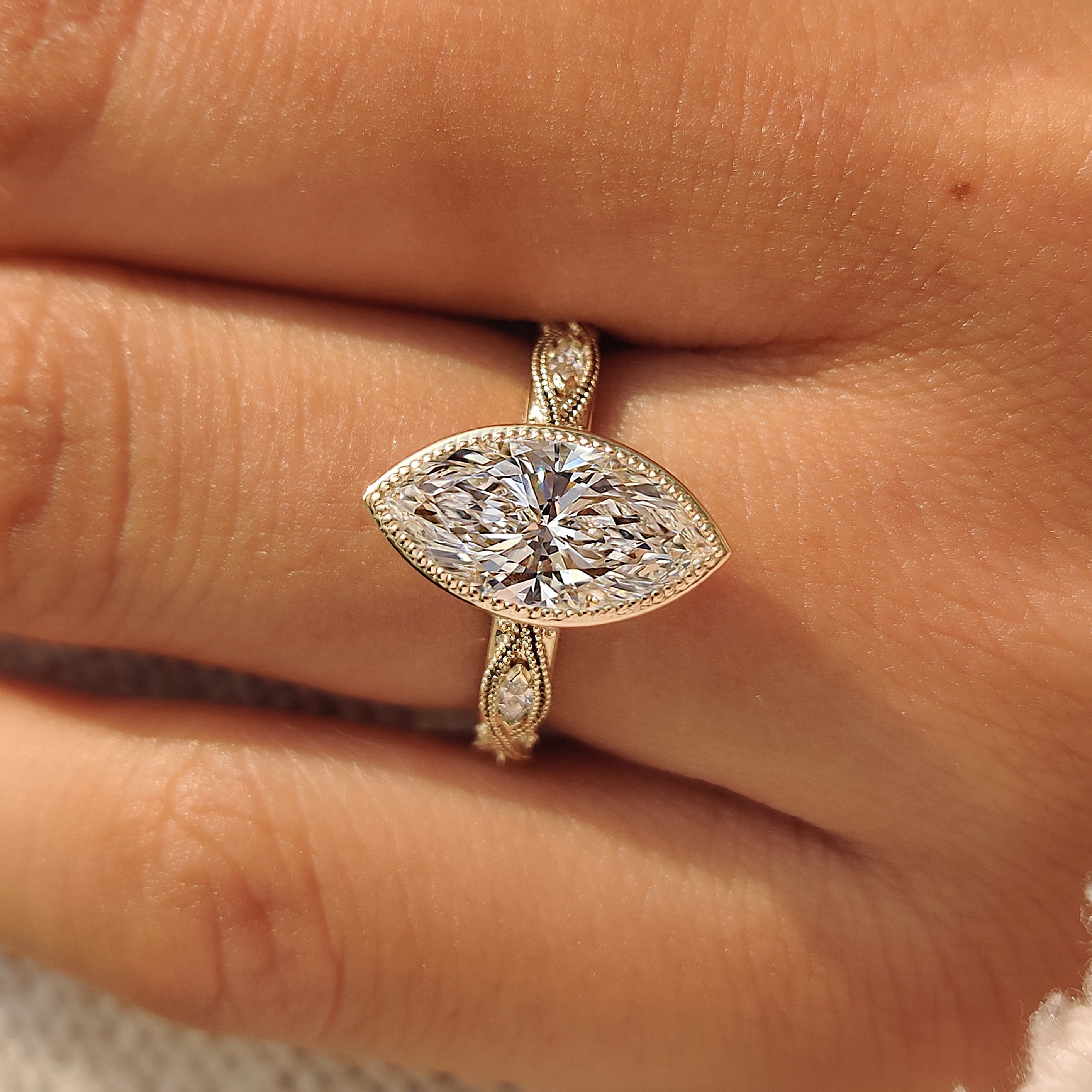 Yellow gold marquise engagement ring with filigree detailing.
