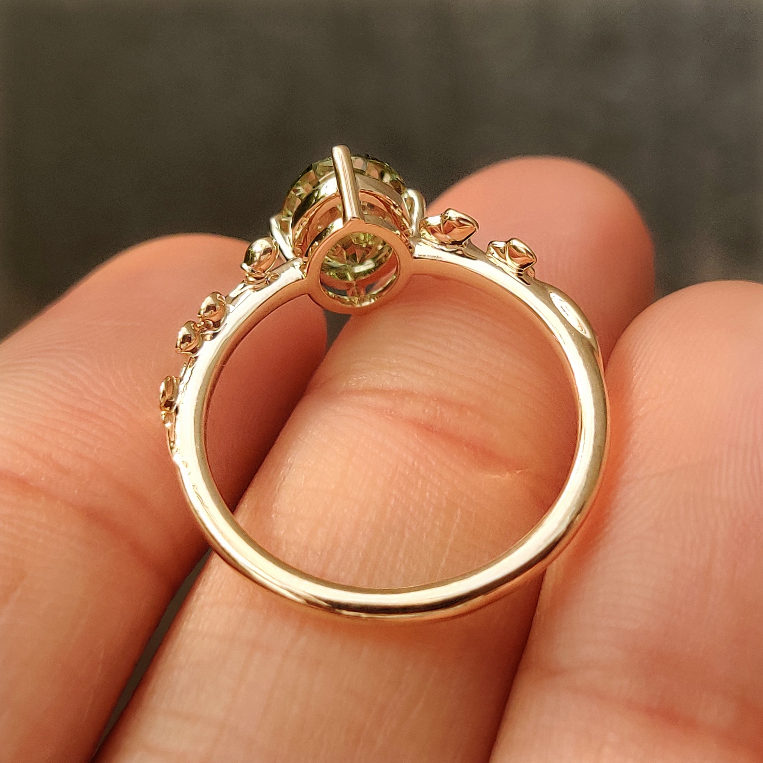 Oval green diamond solitaire ring with compass prongs.
