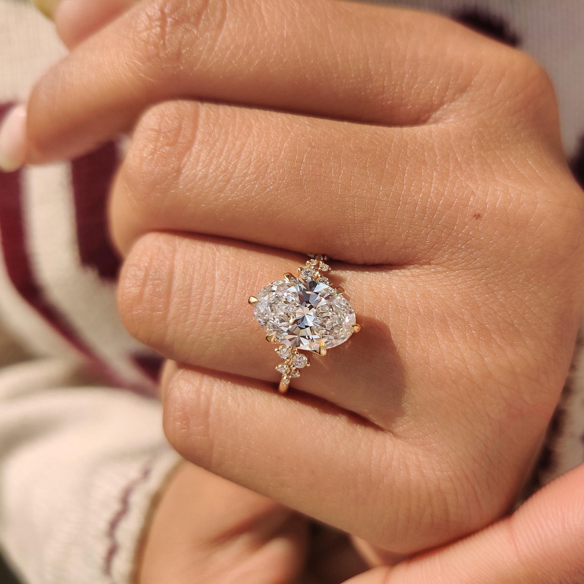 Oval cut diamond ring with round cluster side stones.
