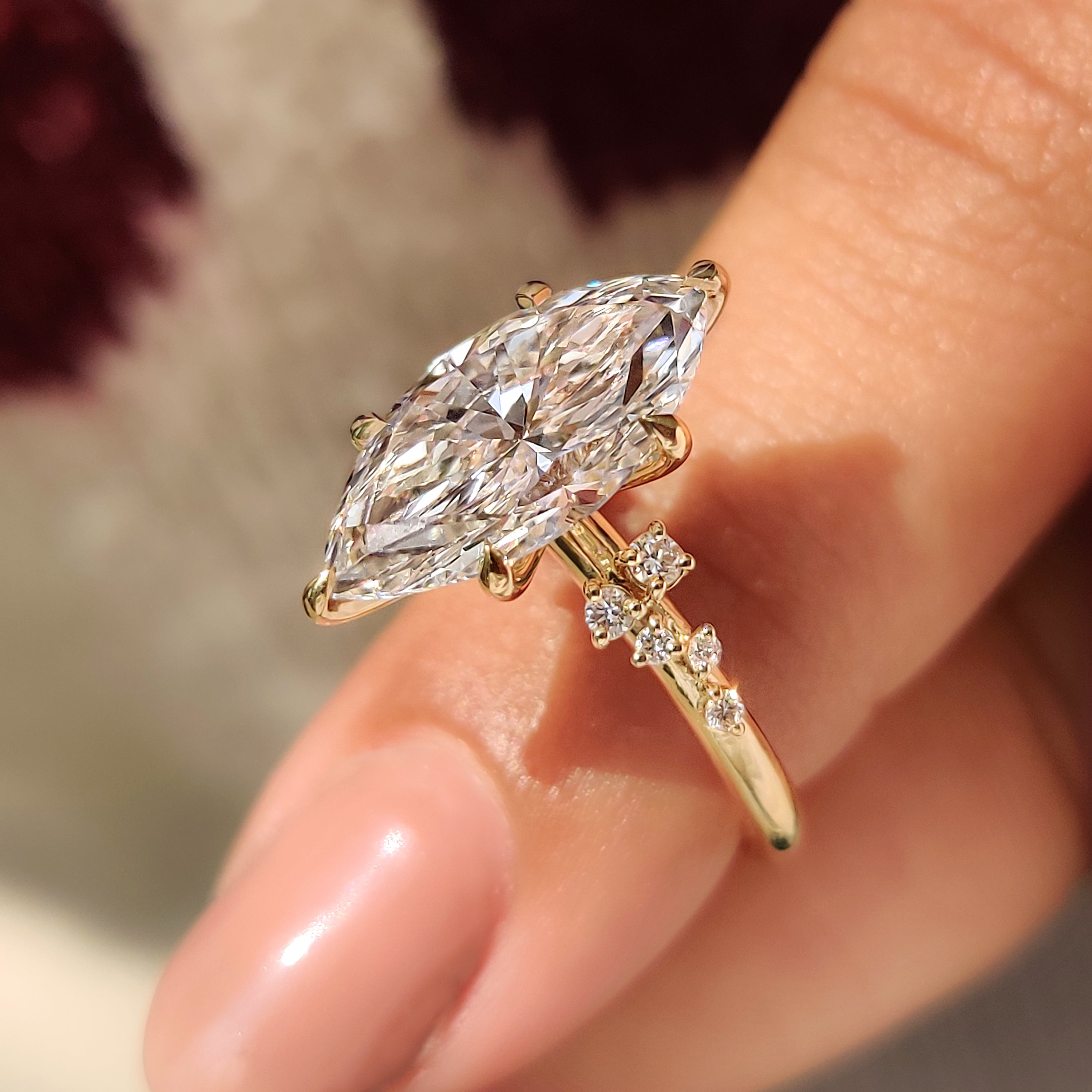 Cluster setting surrounds marquise cut engagement ring with sparkle.
