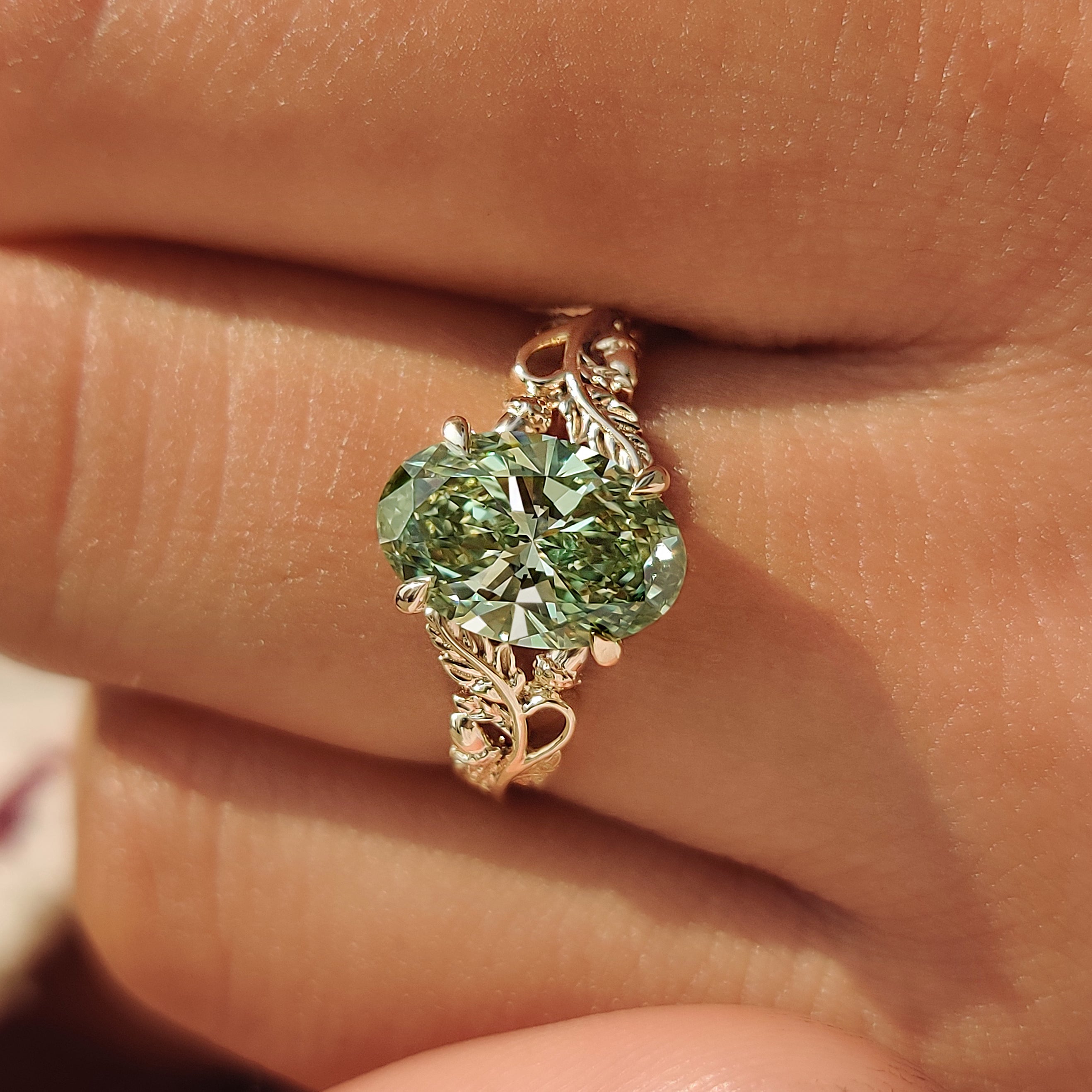 Four claw prong setting on a green oval cut diamond.