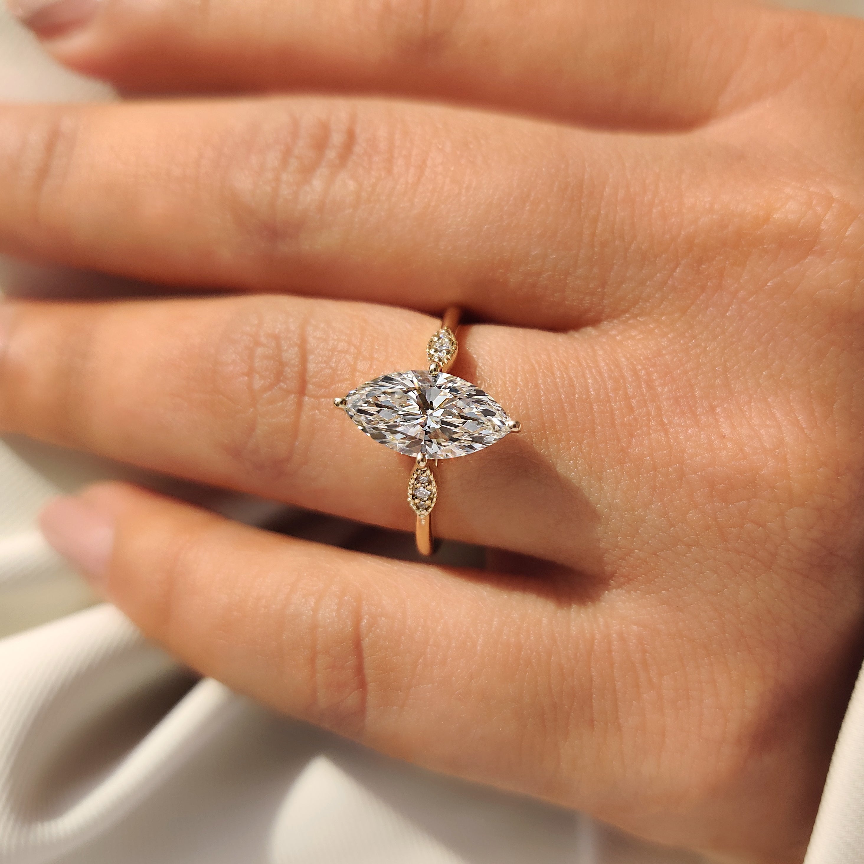 Marquise diamond ring with round accents and cathedral design.

