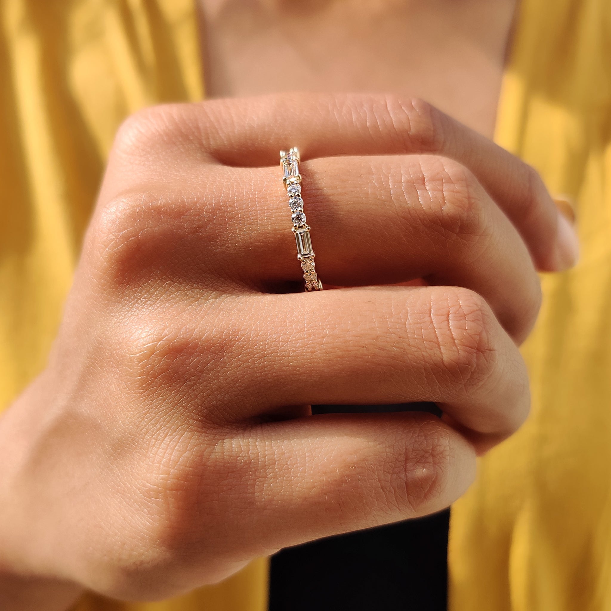 Round and baguette moissanite eternity band crafted from yellow gold.