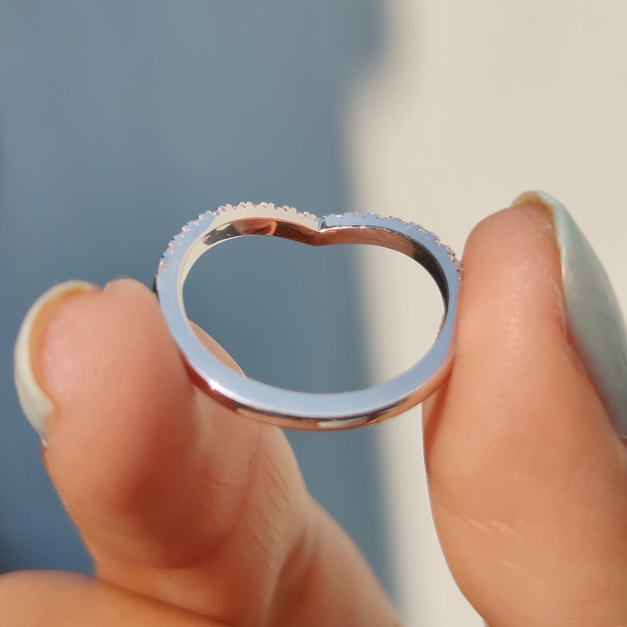 White gold wedding band featuring v shaped curve.
