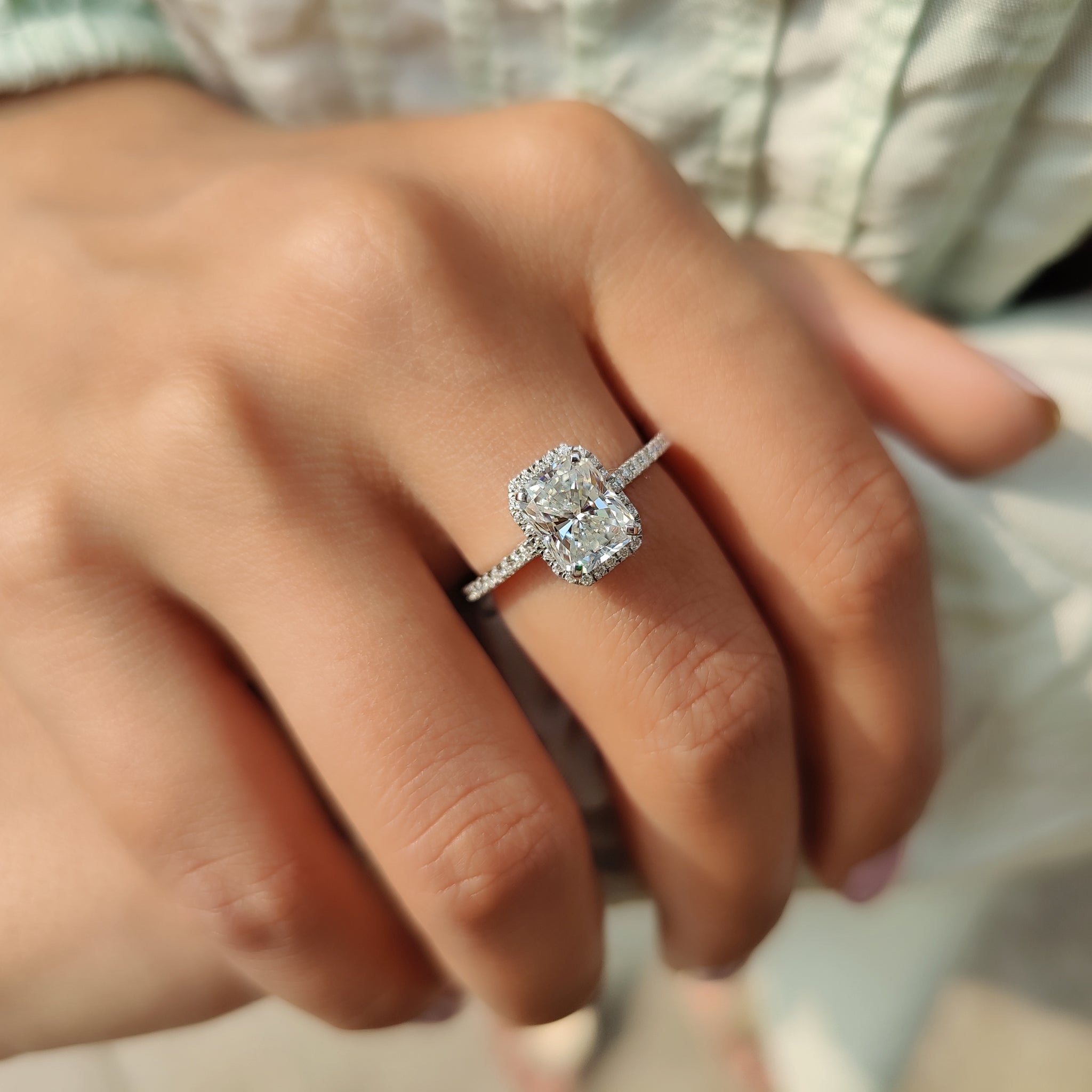 Halo setting moissanite ring with a pave round cut band.