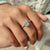 Halo setting moissanite ring with a pave round cut band.