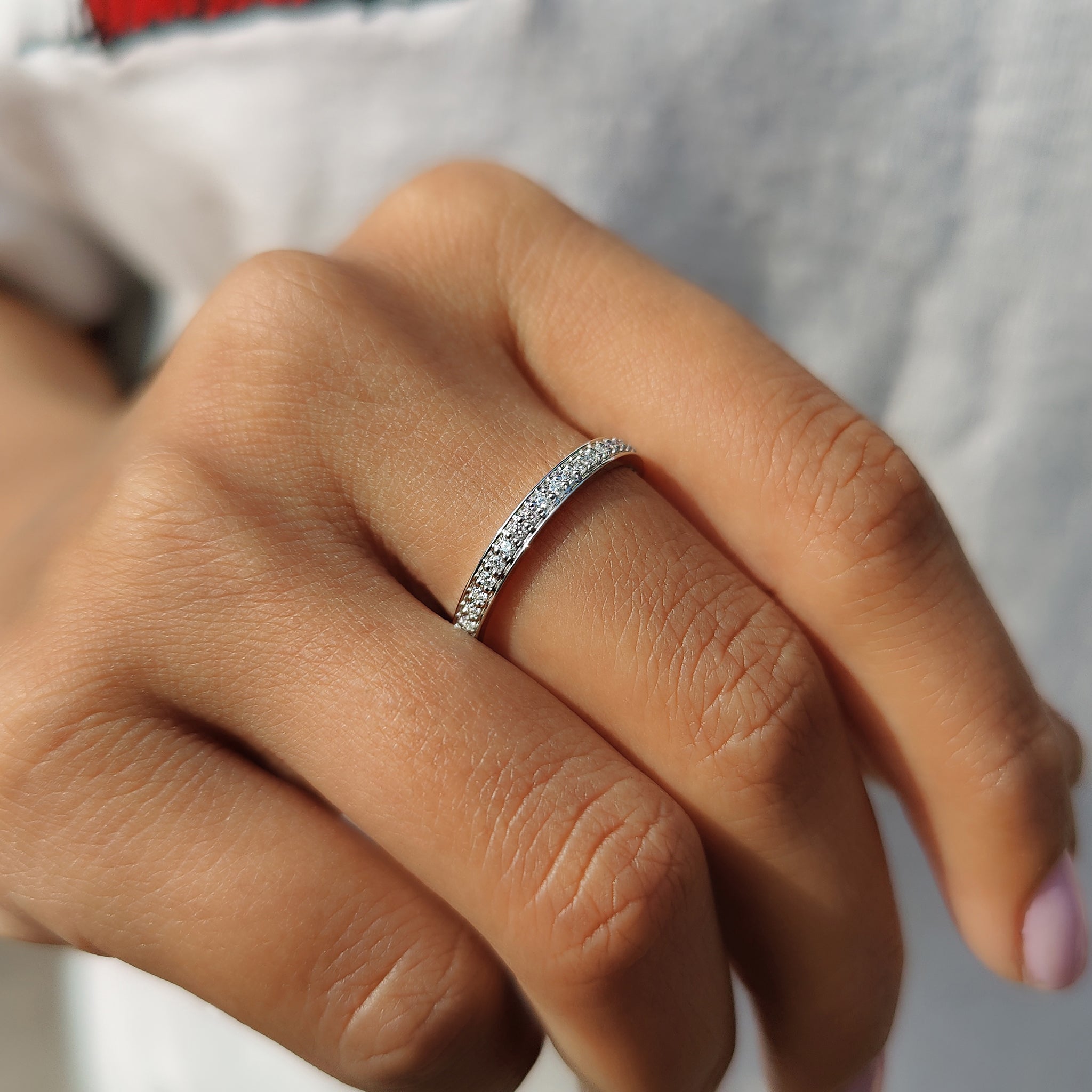 Round moissanite wedding band featuring a prong set design.